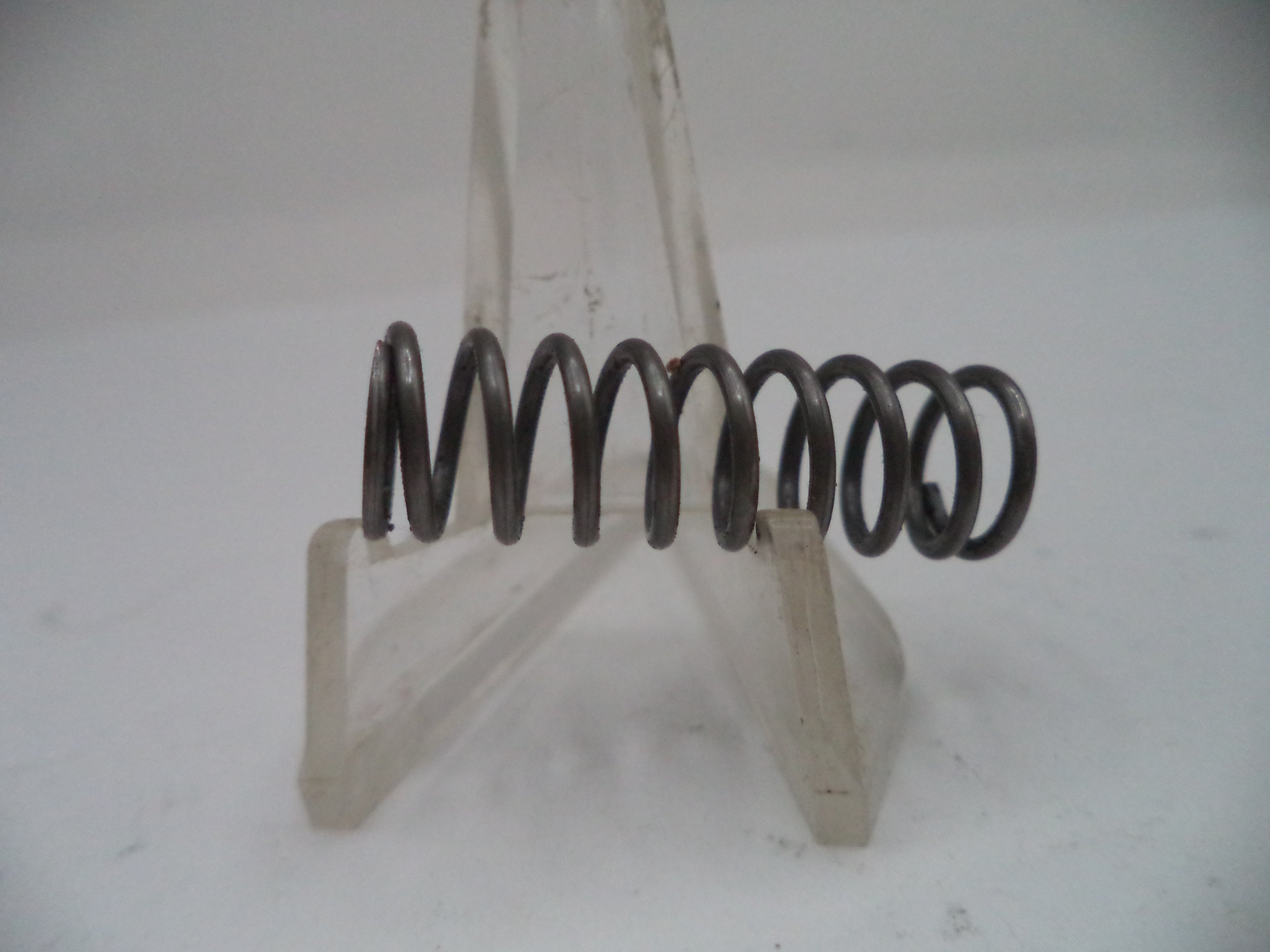 Coiled spring on a stand against a white background