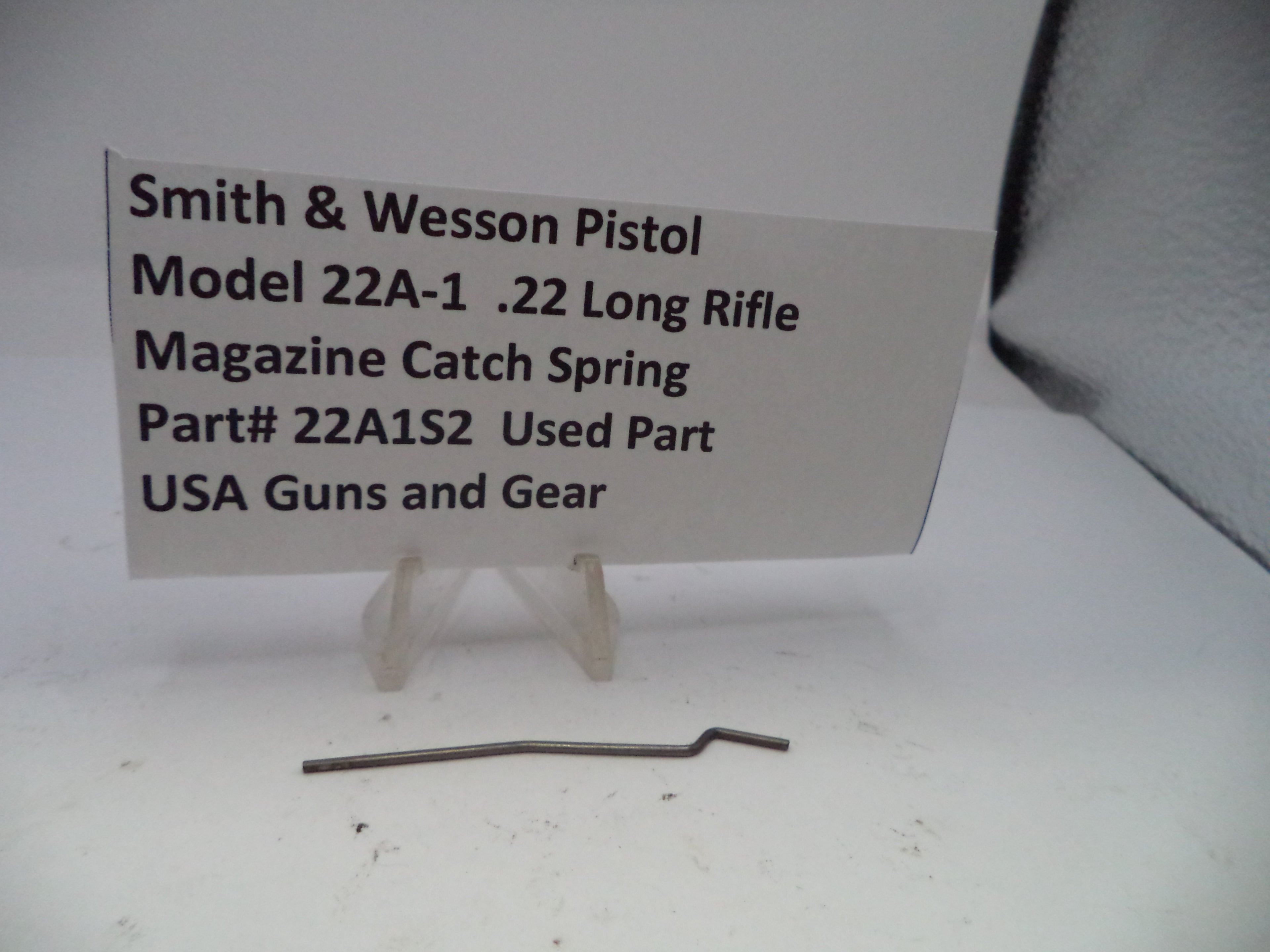 Smith & Wesson pistol magazine catch spring on a white background with a label.