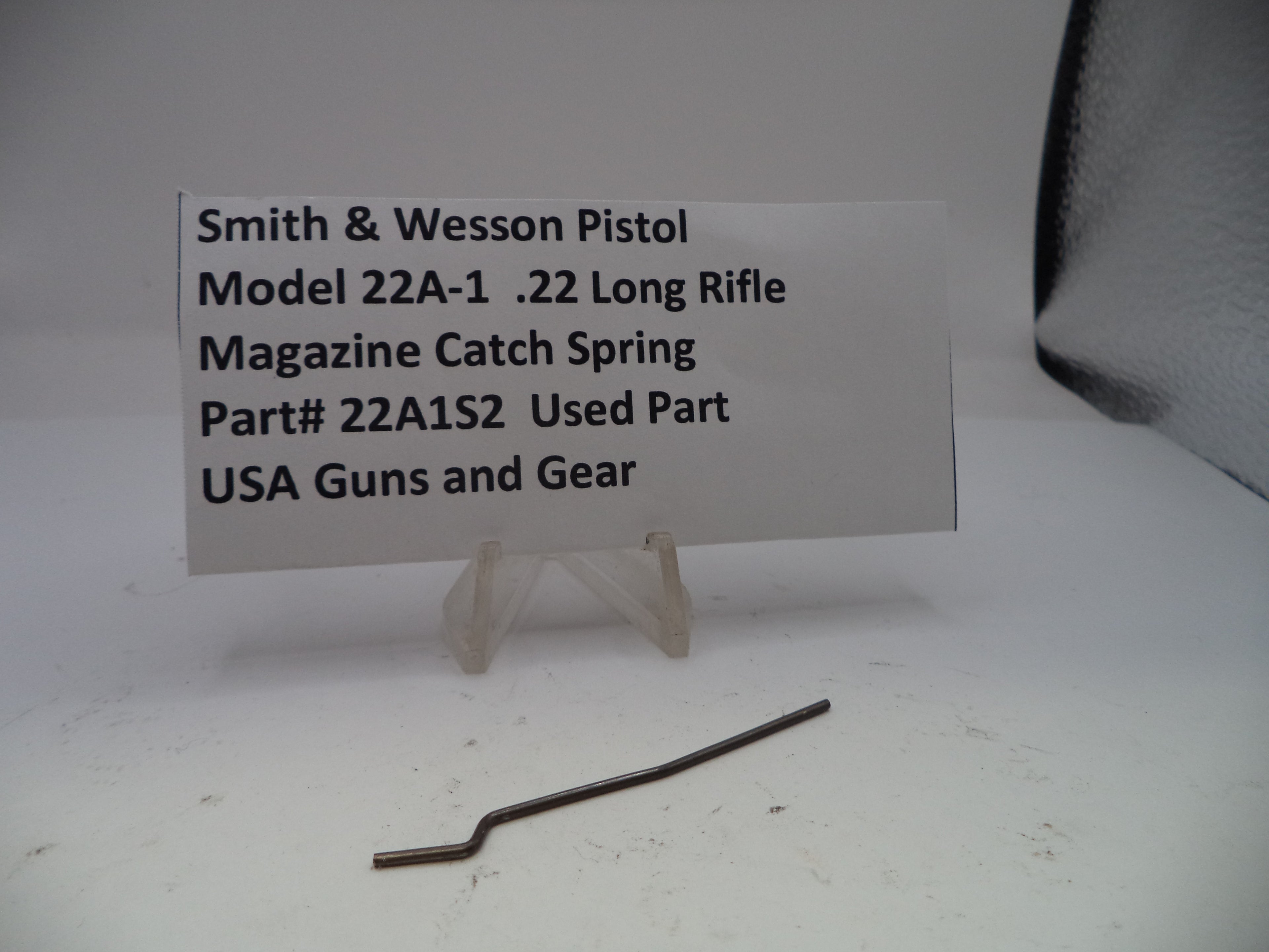 Smith & Wesson pistol magazine catch spring with a label on a white background