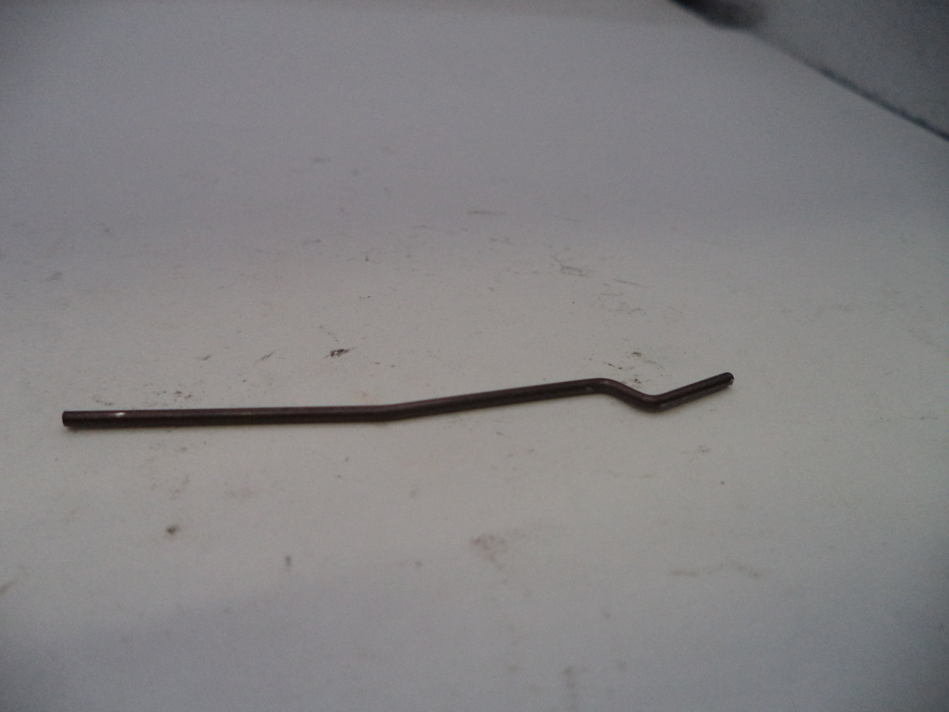 Metallic curved rod on a white surface