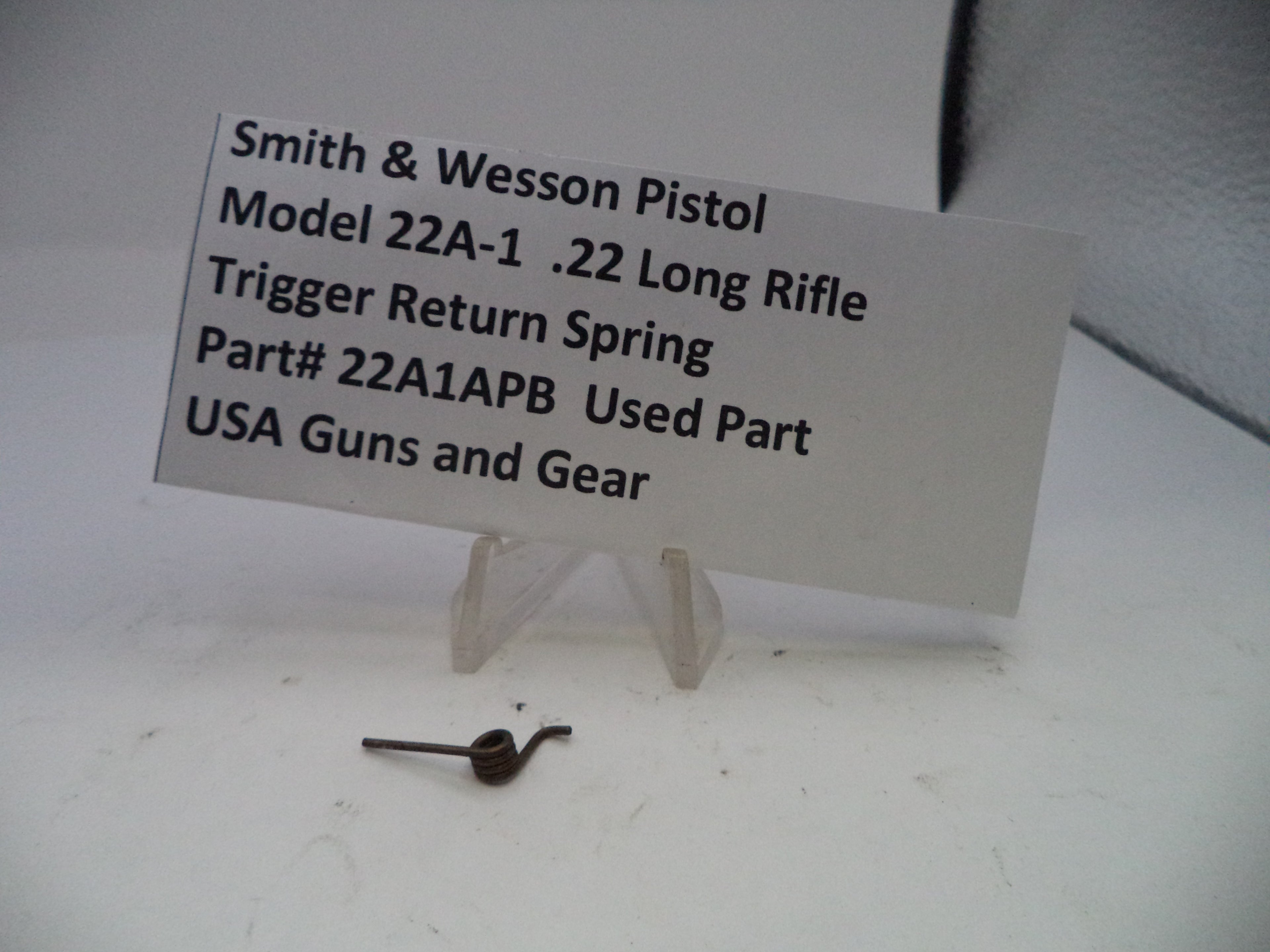 Smith & Wesson pistol trigger return spring with a label on a white background