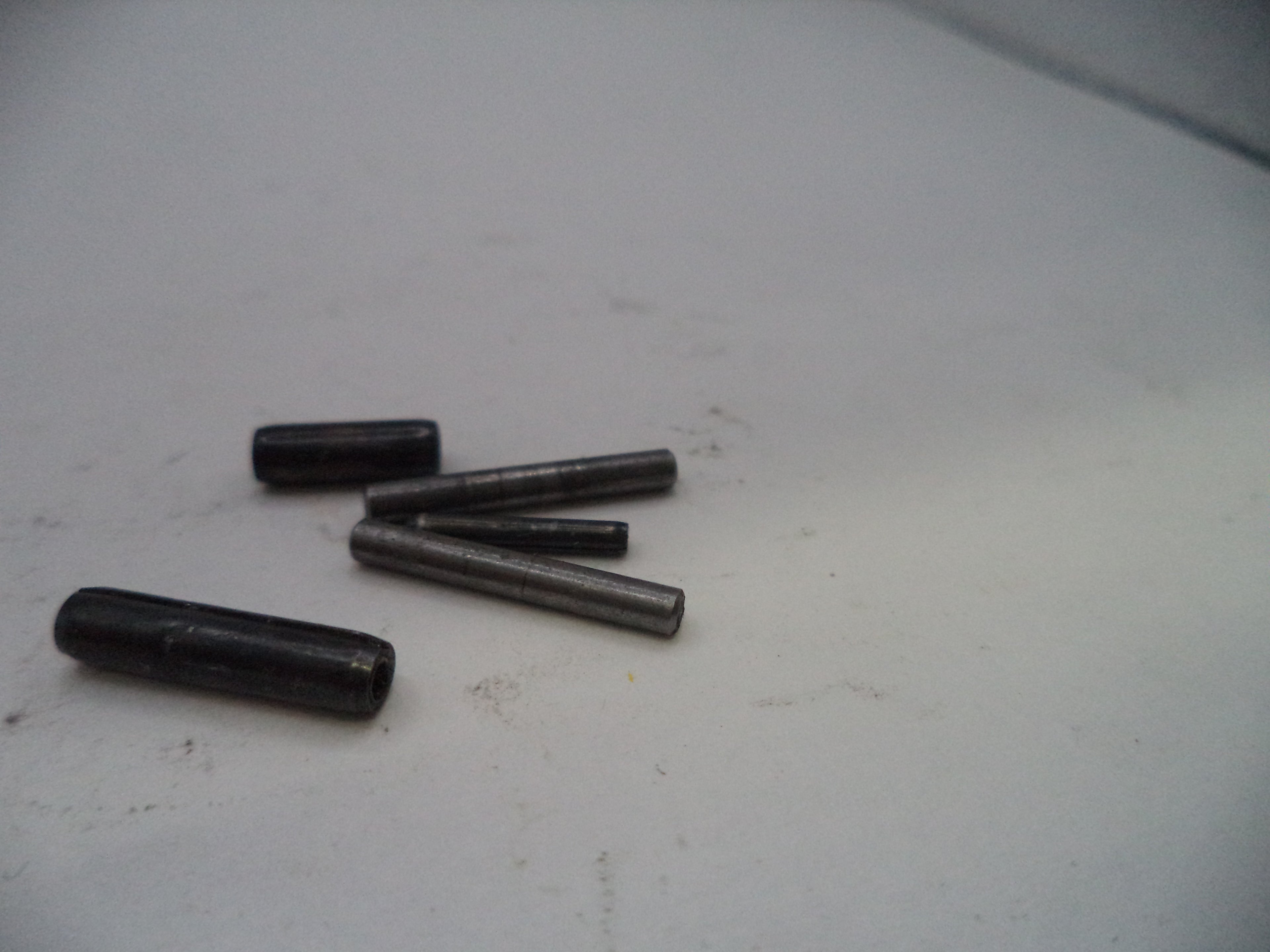 Four black cylindrical objects on a light gray surface