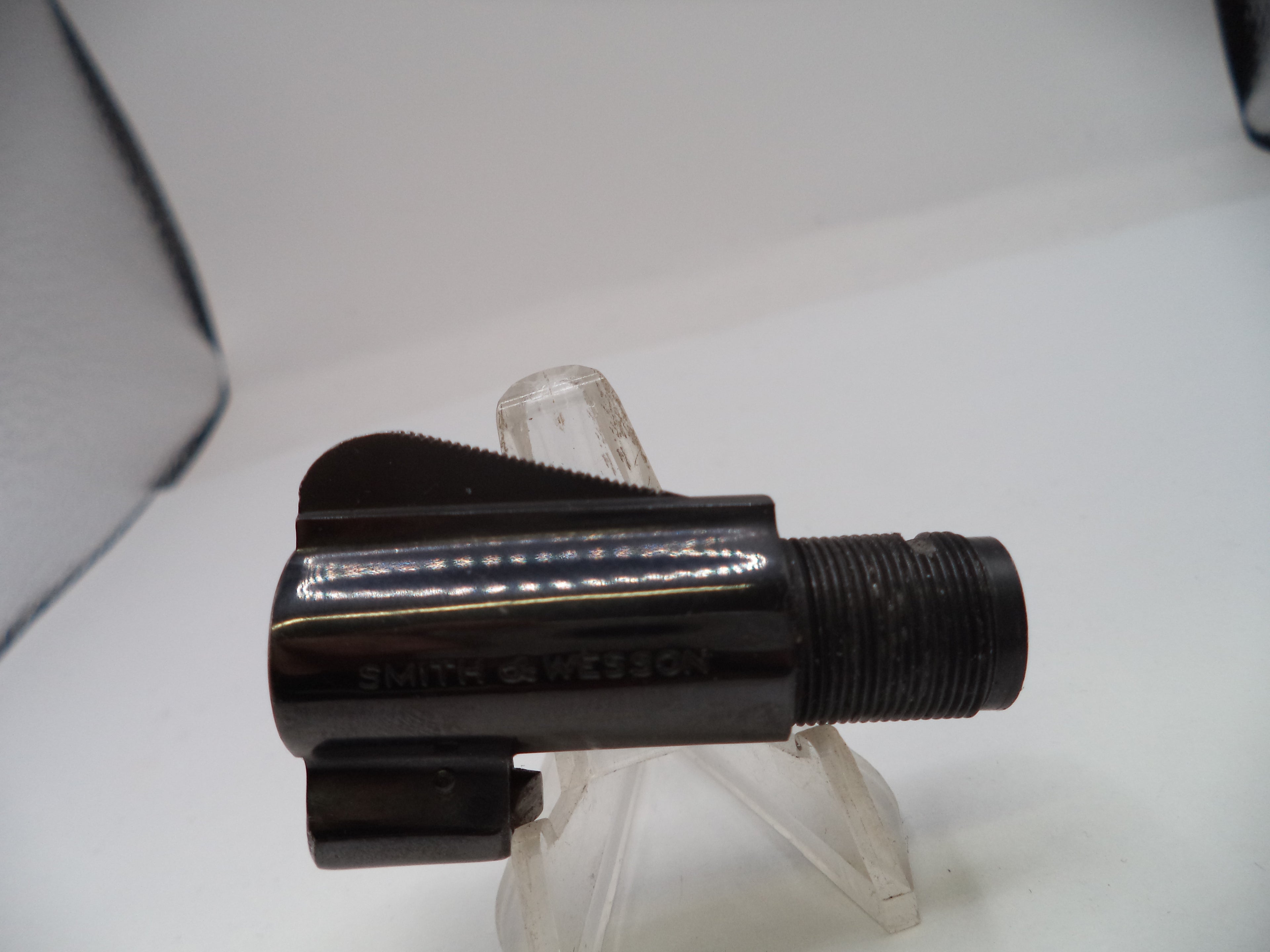 Black metal fitting on a clear stand against a white background