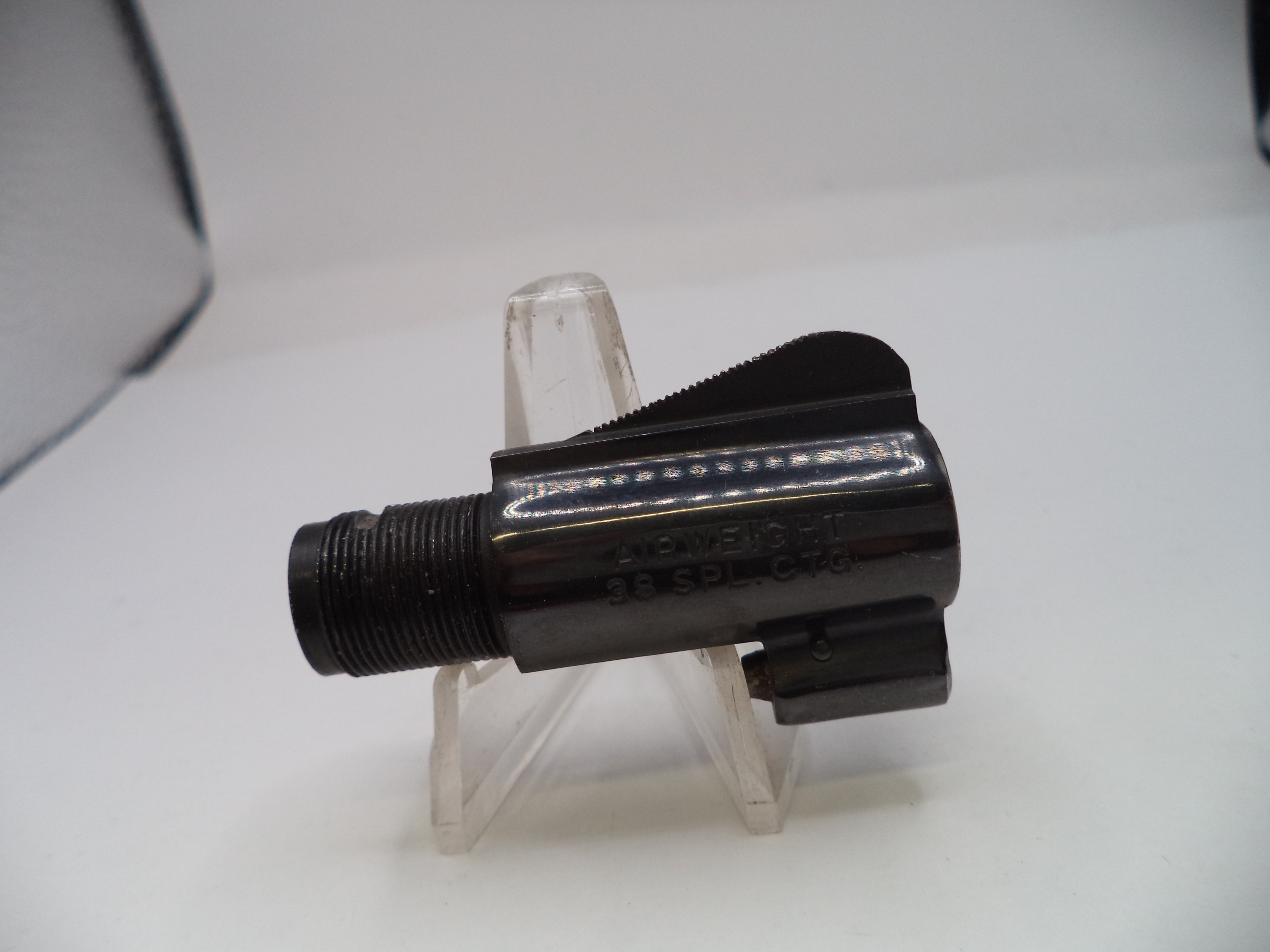 Black mechanical component on a clear stand against a white background