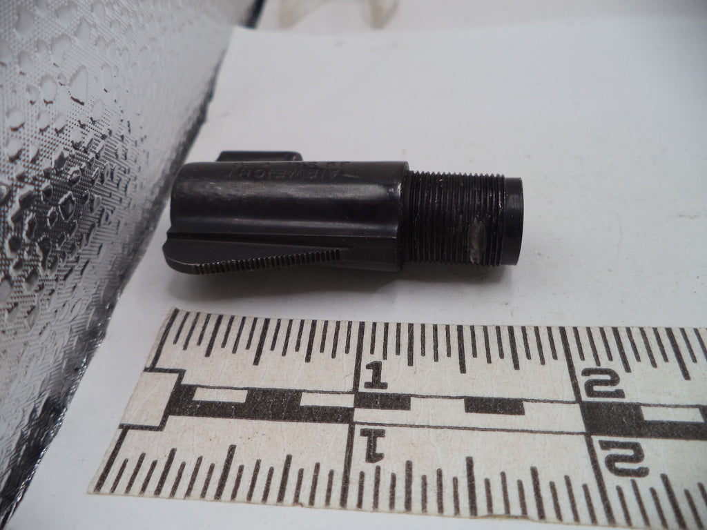Black cylindrical object on a white surface with a ruler for scale.
