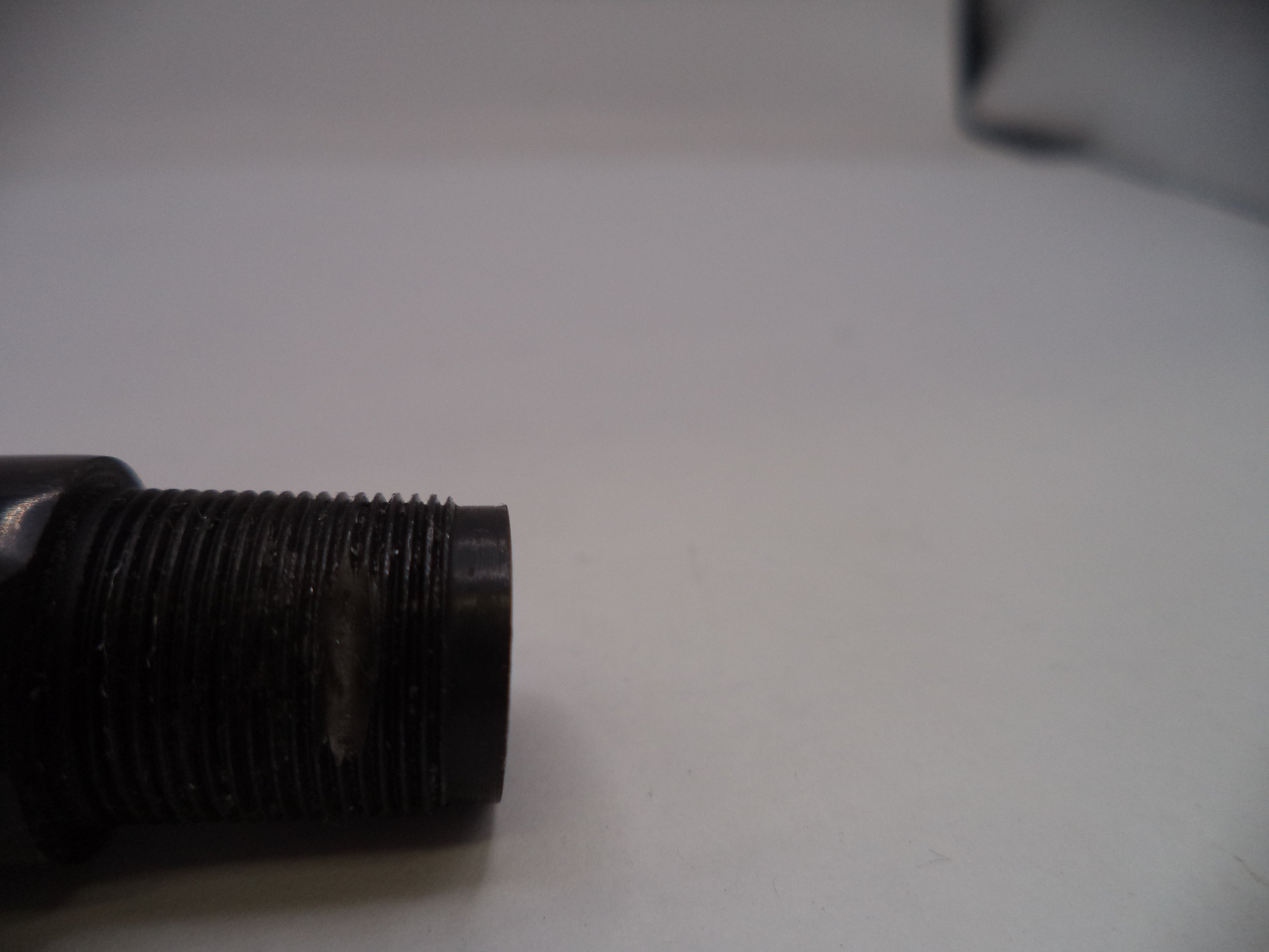 Close-up of a black threaded metal screw on a light gray background