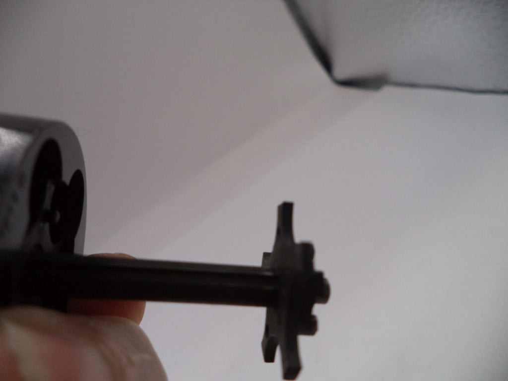 Close-up of a mechanical component held by a hand against a white background