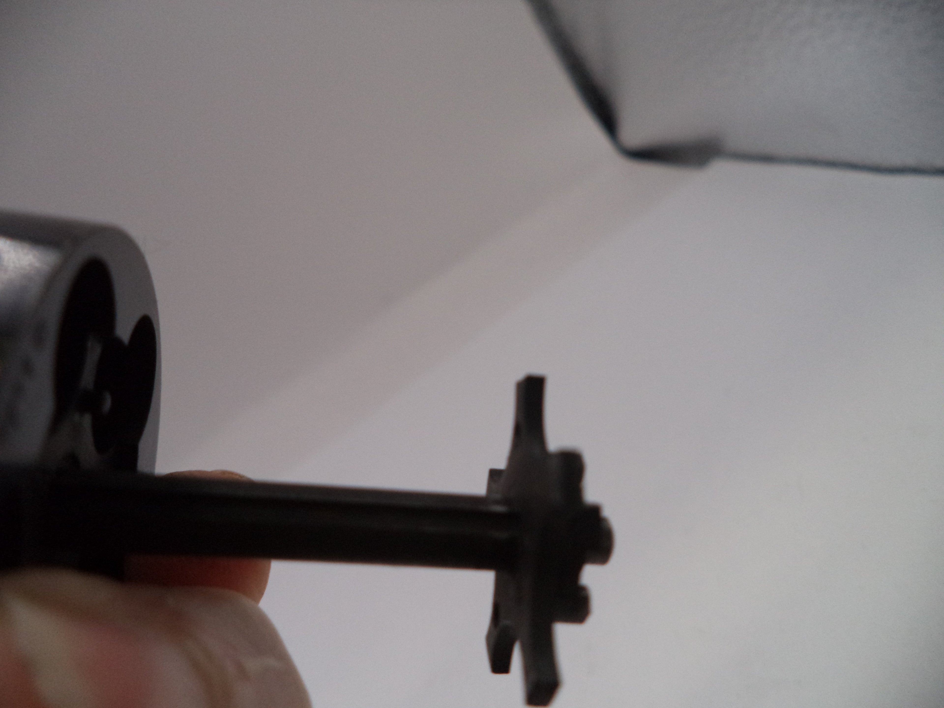 Close-up of a mechanical component held by a hand against a white background
