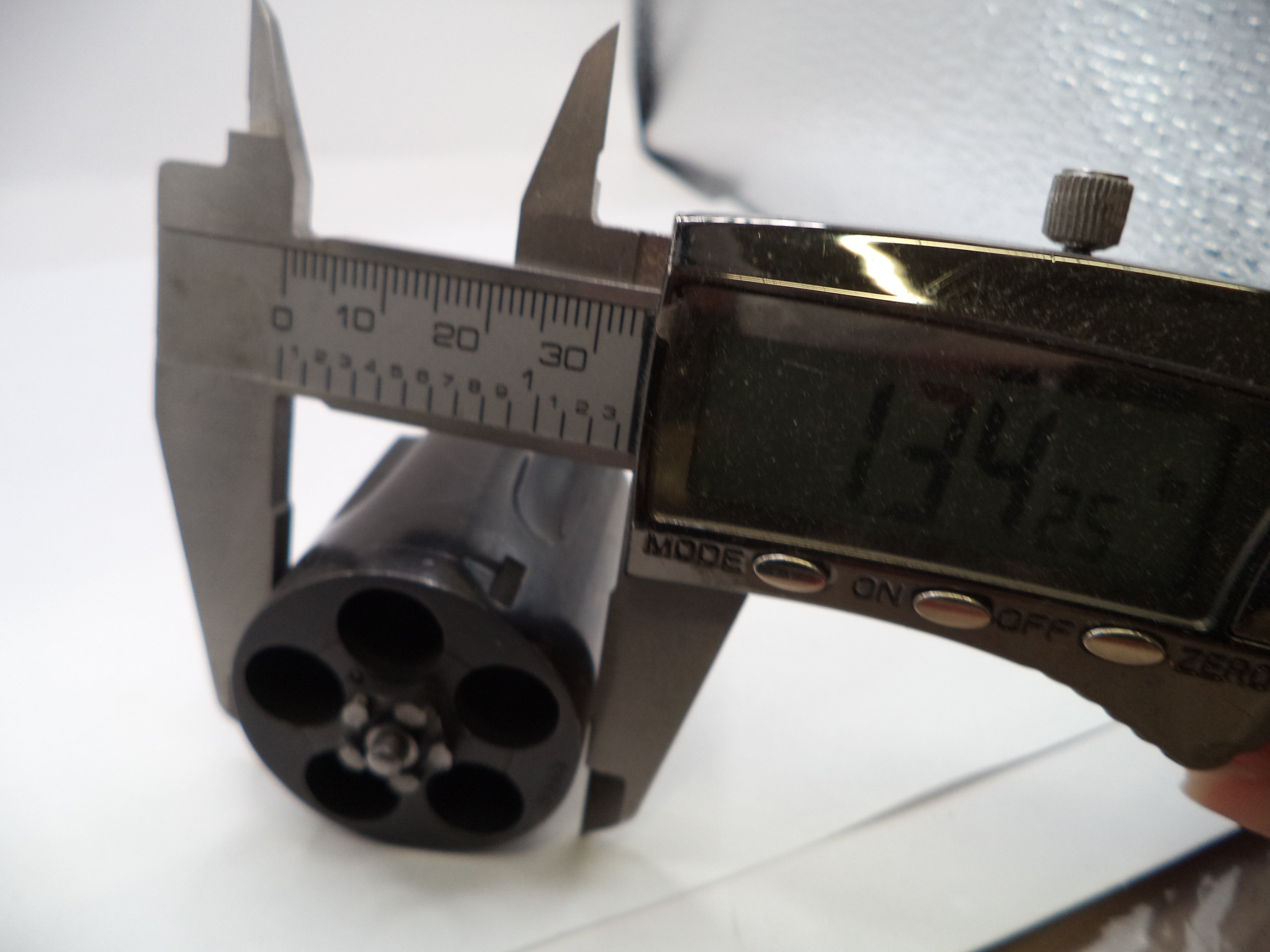 Digital caliper measuring a revolver barrel on a white background