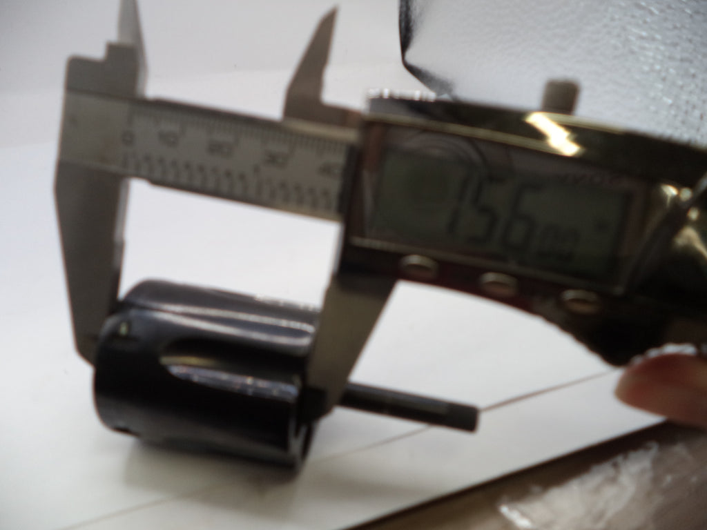 Digital caliper measuring a black cylindrical object on a white surface