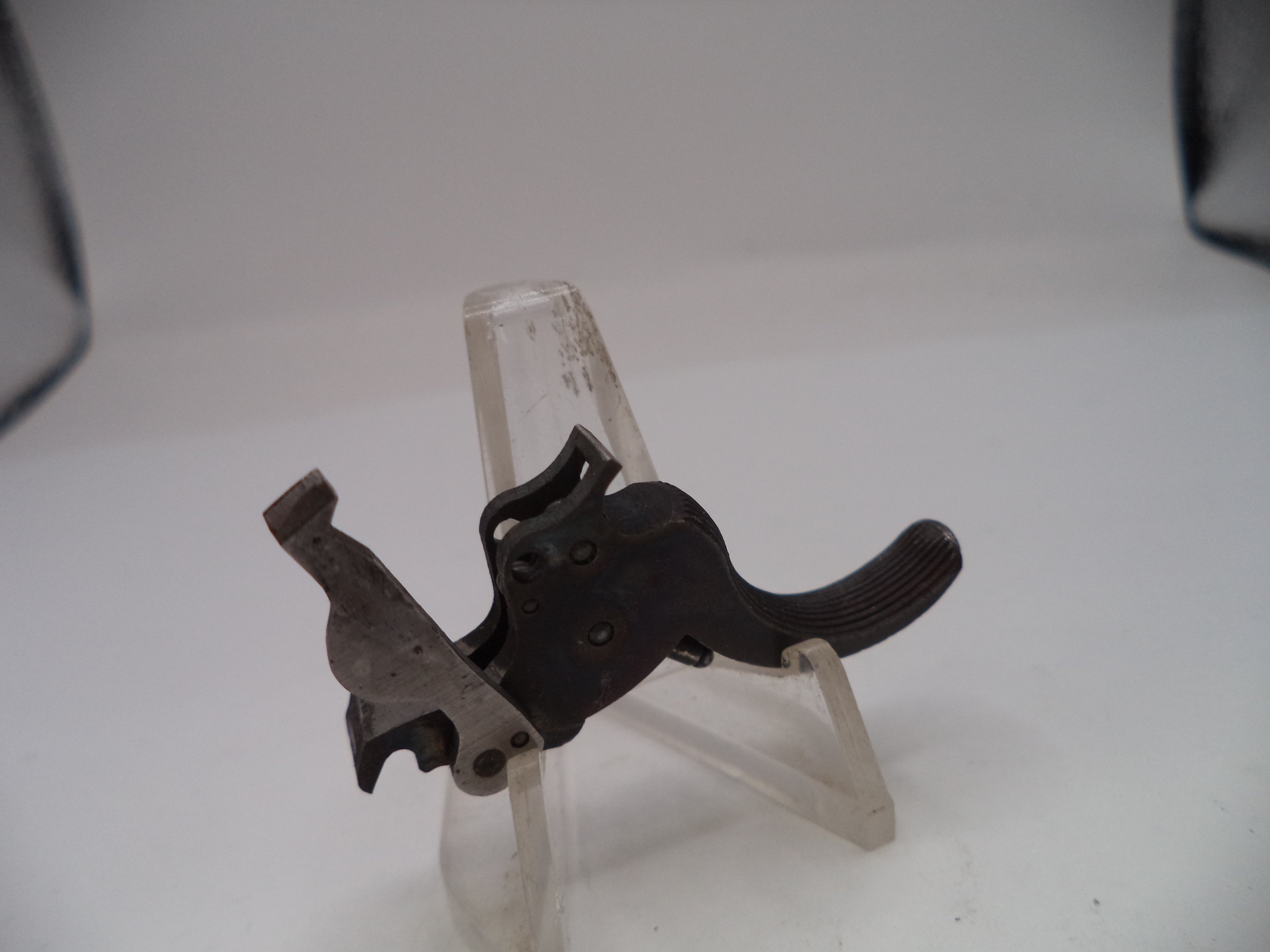 Metallic object on a clear stand against a white background