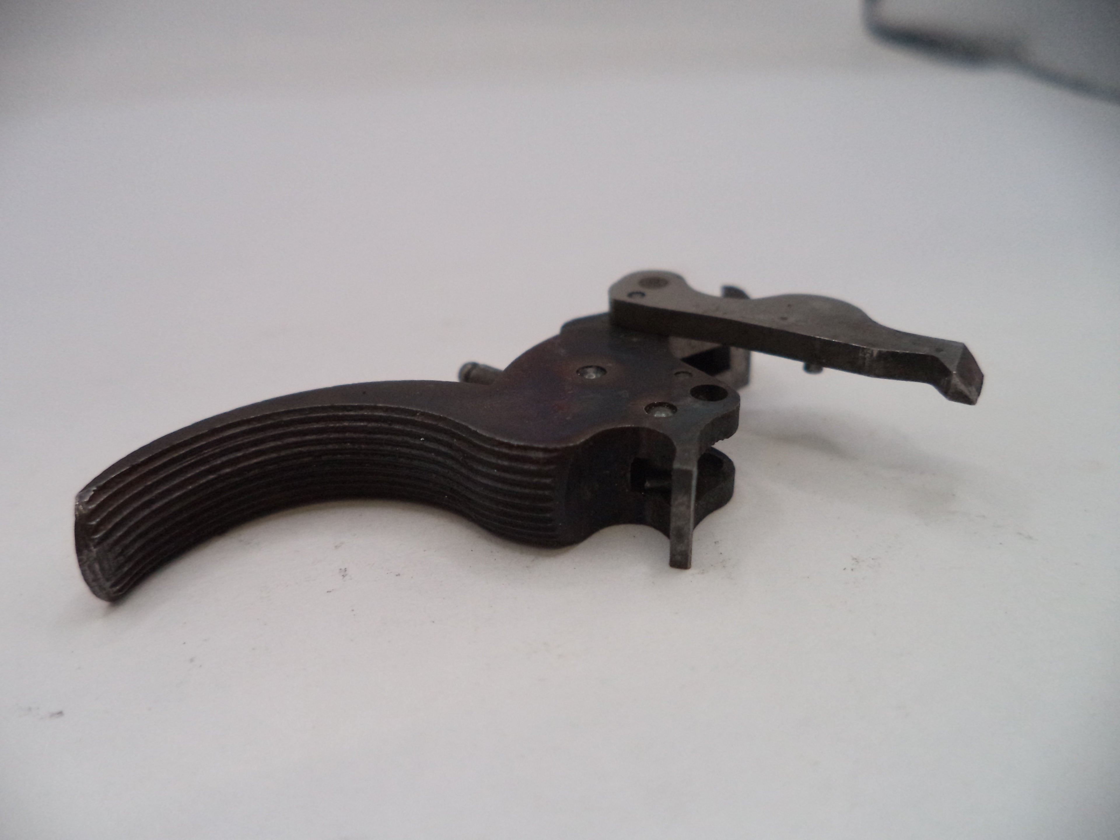 Metallic firearm trigger on a white surface