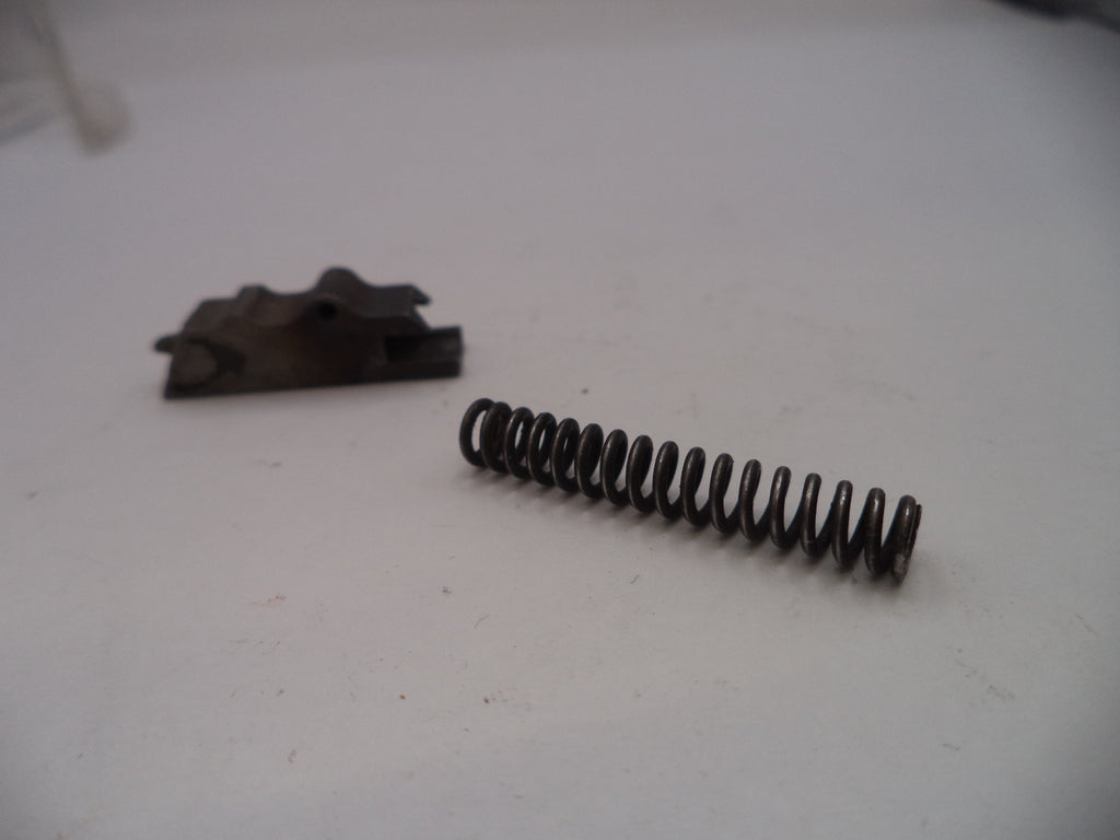 Coiled spring and metal bracket on a white surface