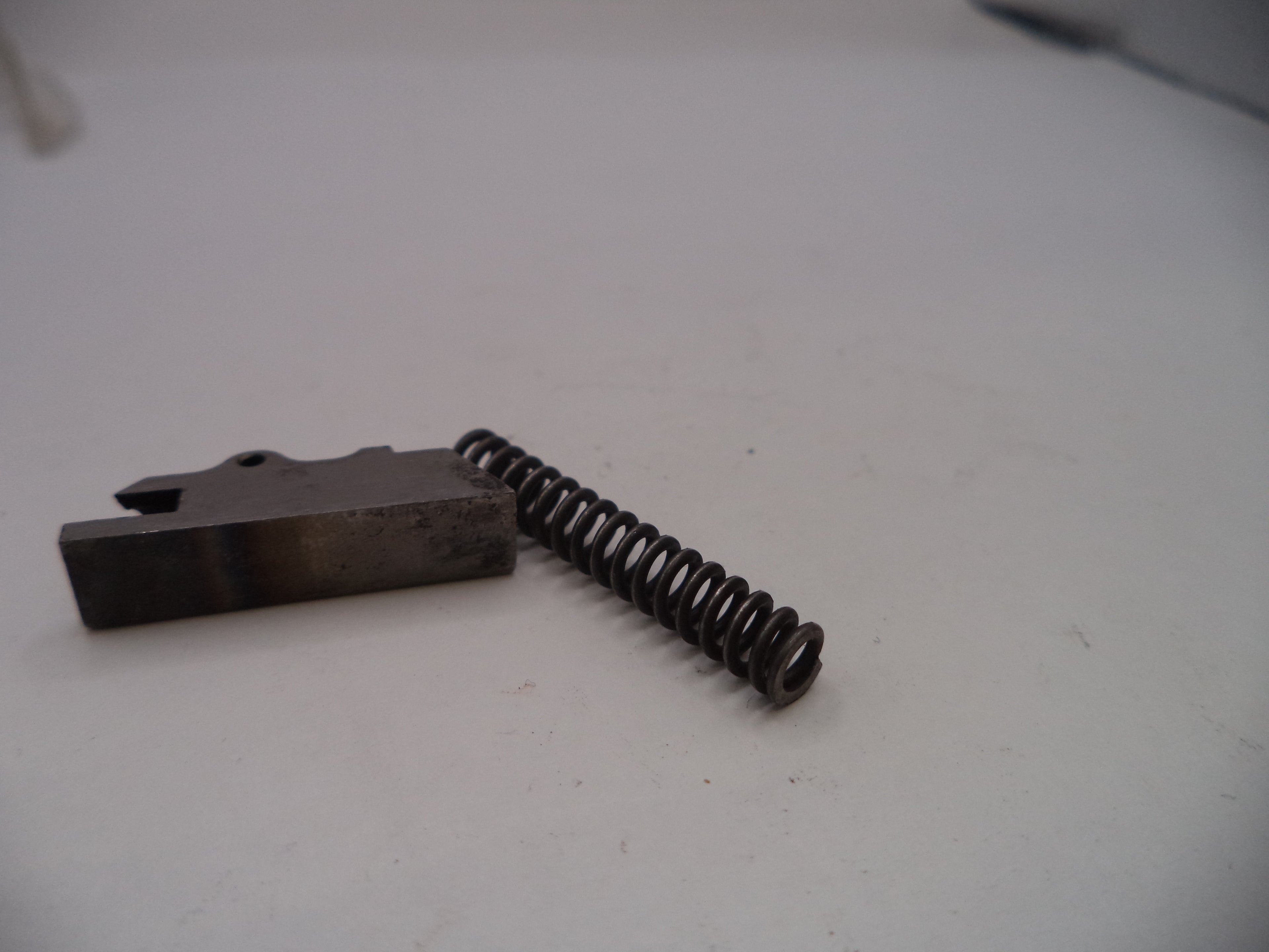 Metal component with a spring on a white surface