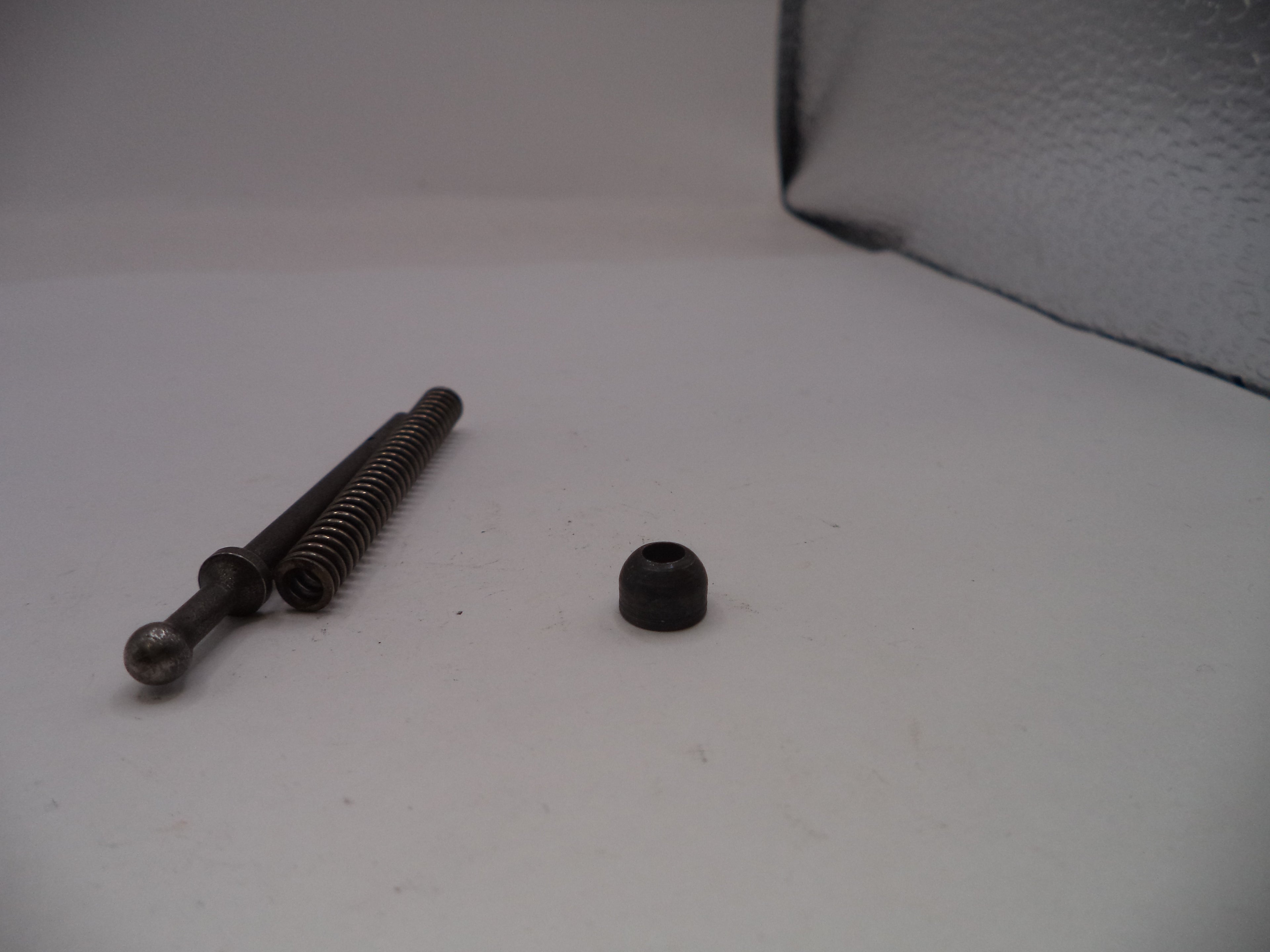 Two metal screws on a white surface with a gray textured background