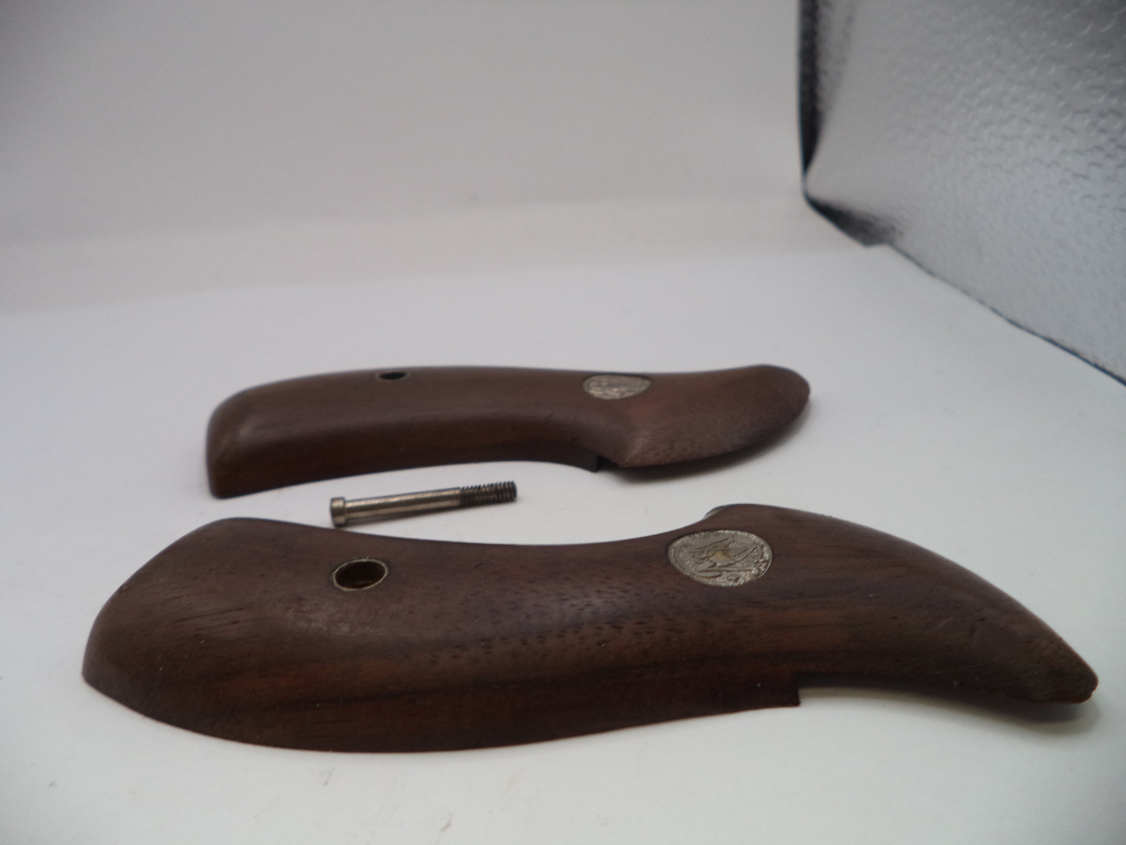 Two brown wooden handles with metal pins on a white surface