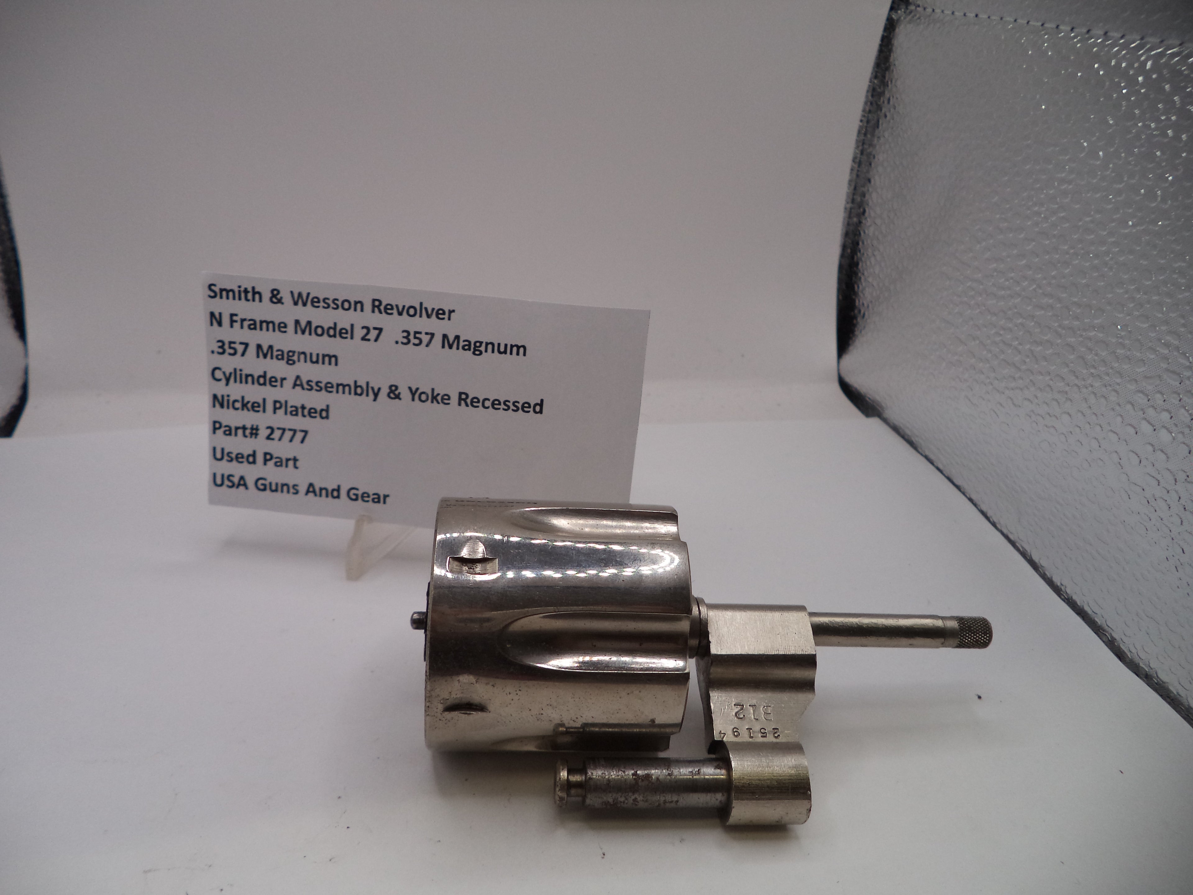Smith & Wesson revolver cylinder on a white surface with a label in the background
