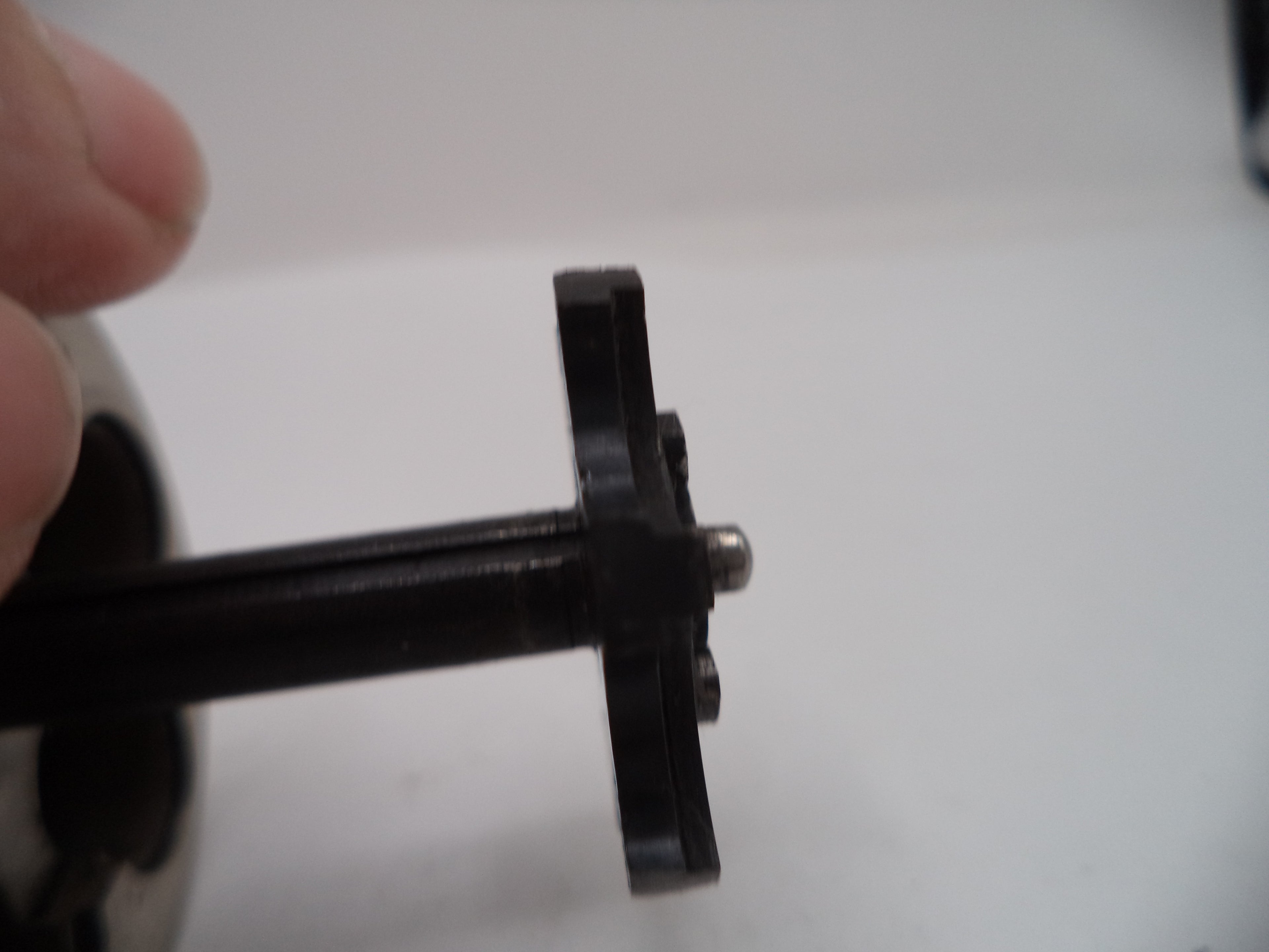 Close-up of a black mechanical component held by a hand on a white background