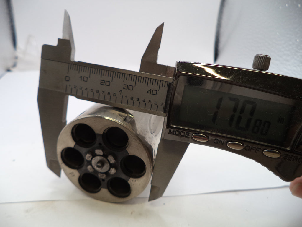 Metal cylindrical object with multiple holes being measured by a digital caliper on a white background