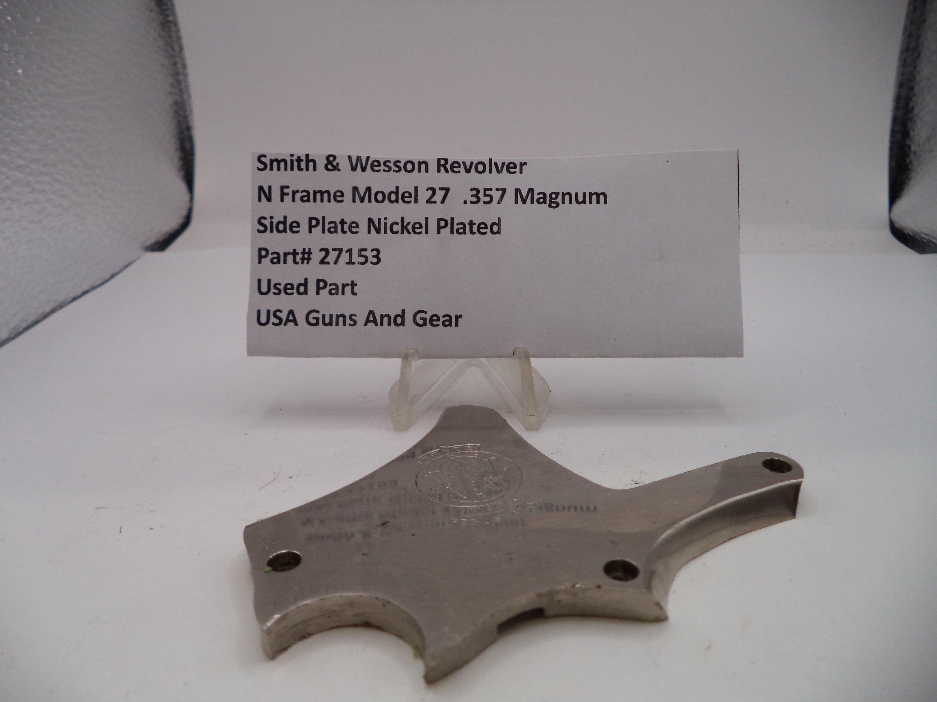Smith & Wesson revolver side plate with a label on a white background