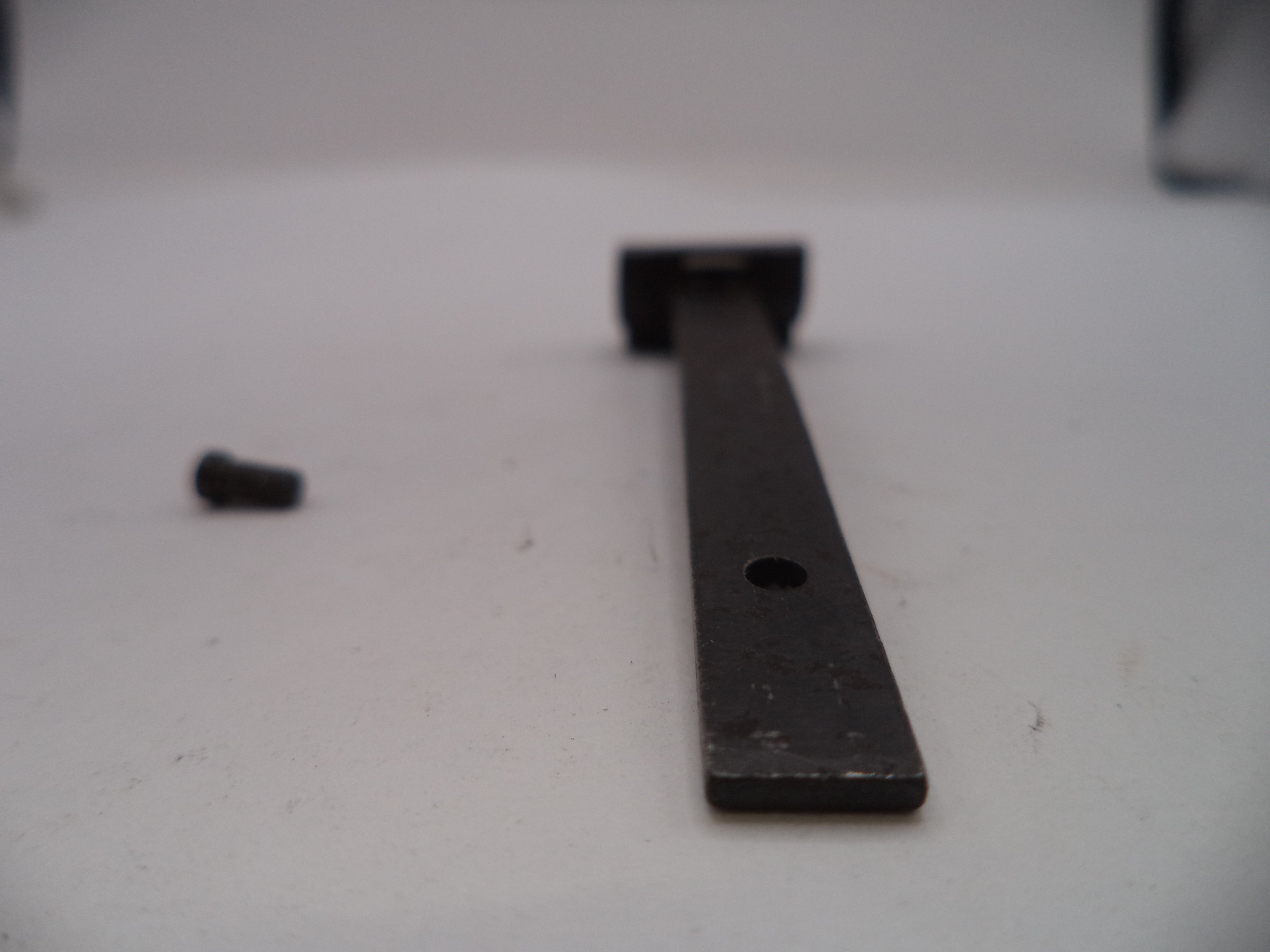 Long metal bar with a hole on a white surface