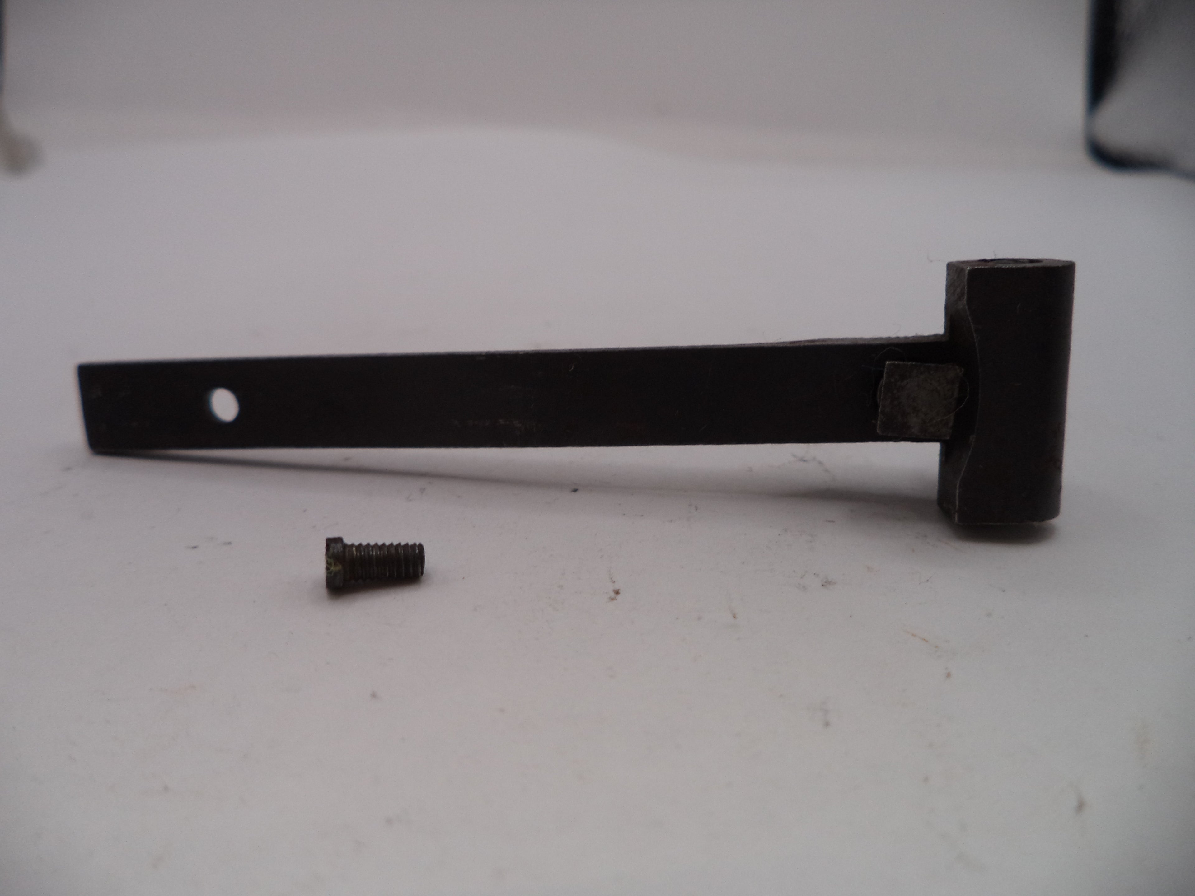 Black metal bar with a small screw on a white surface