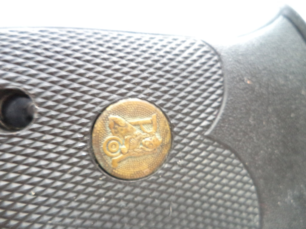Close-up of a textured gun grip with a gold emblem featuring a horse and carriage.
