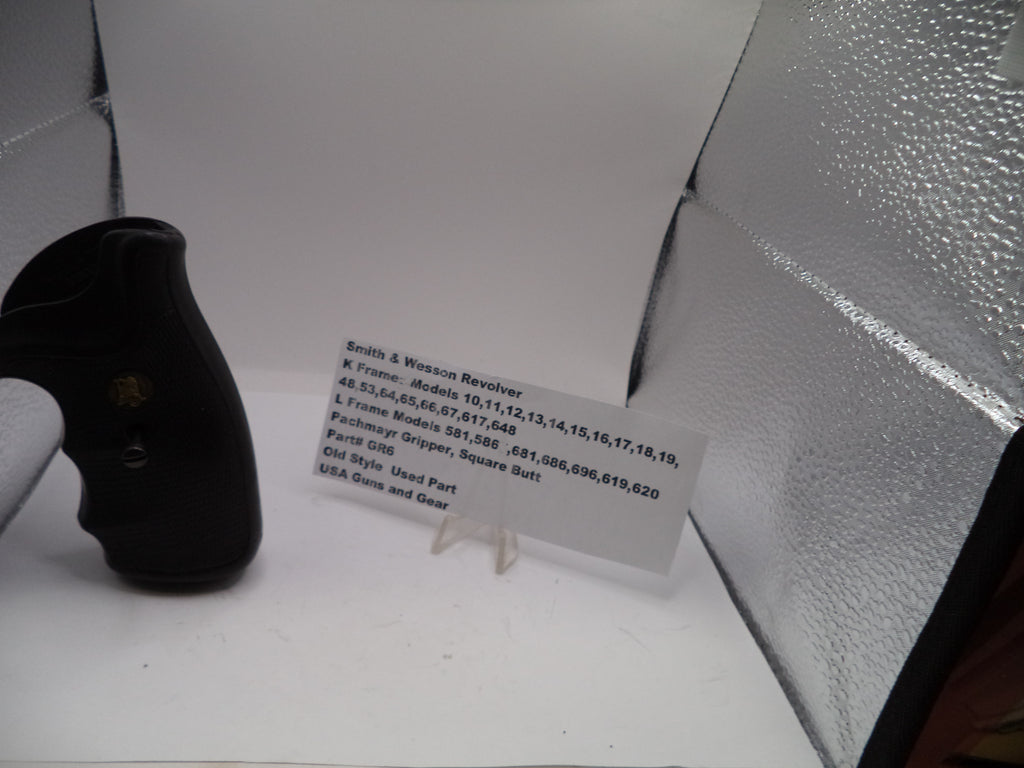Black handgun on a white surface with text on a white card behind it