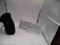 Black handgun on a white surface with text on a white card behind it