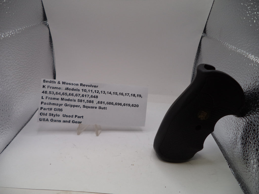 Black gun grip on a white surface with a label in the background