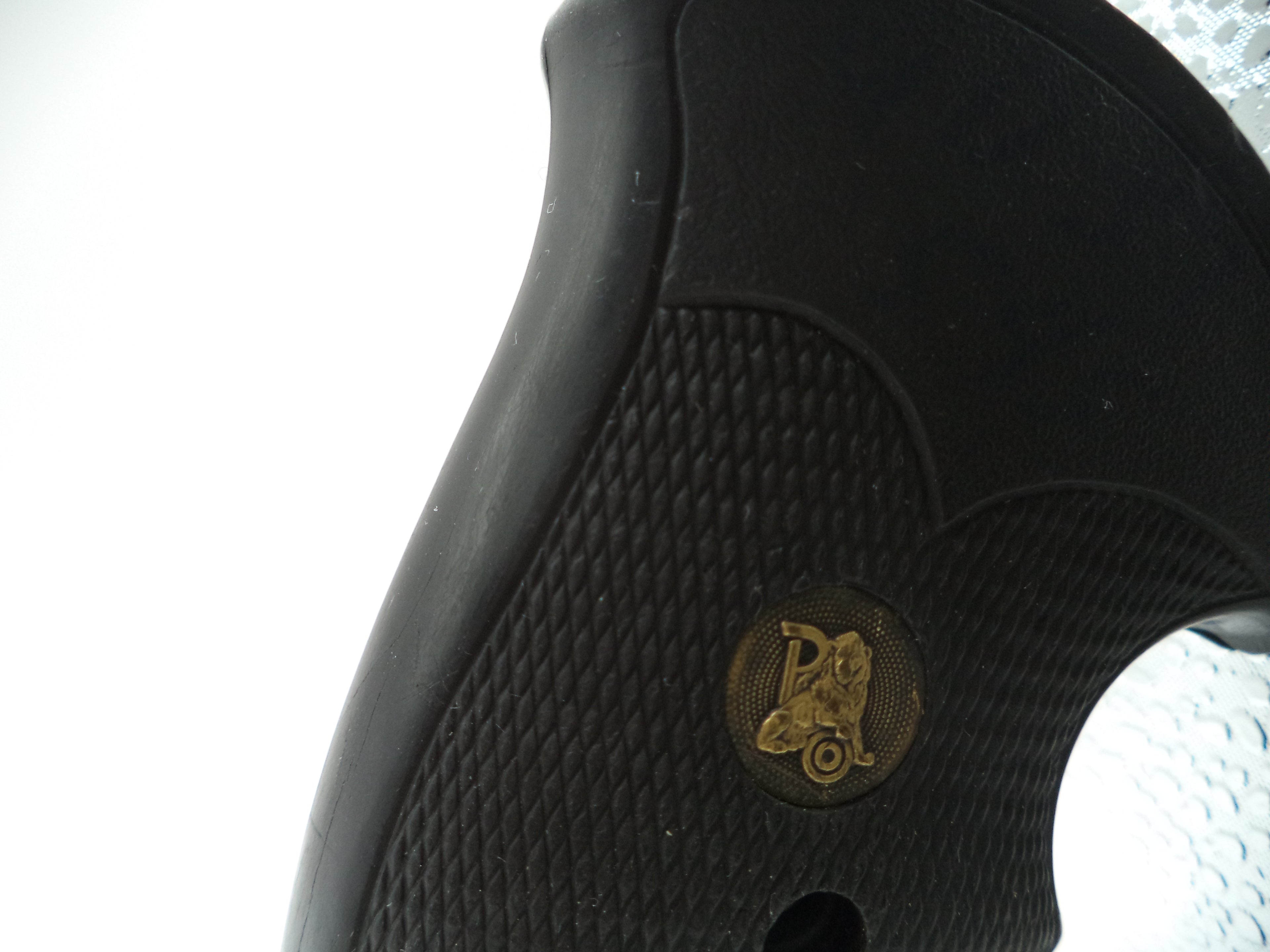 Close-up of a black gun grip with a gold emblem on a white background