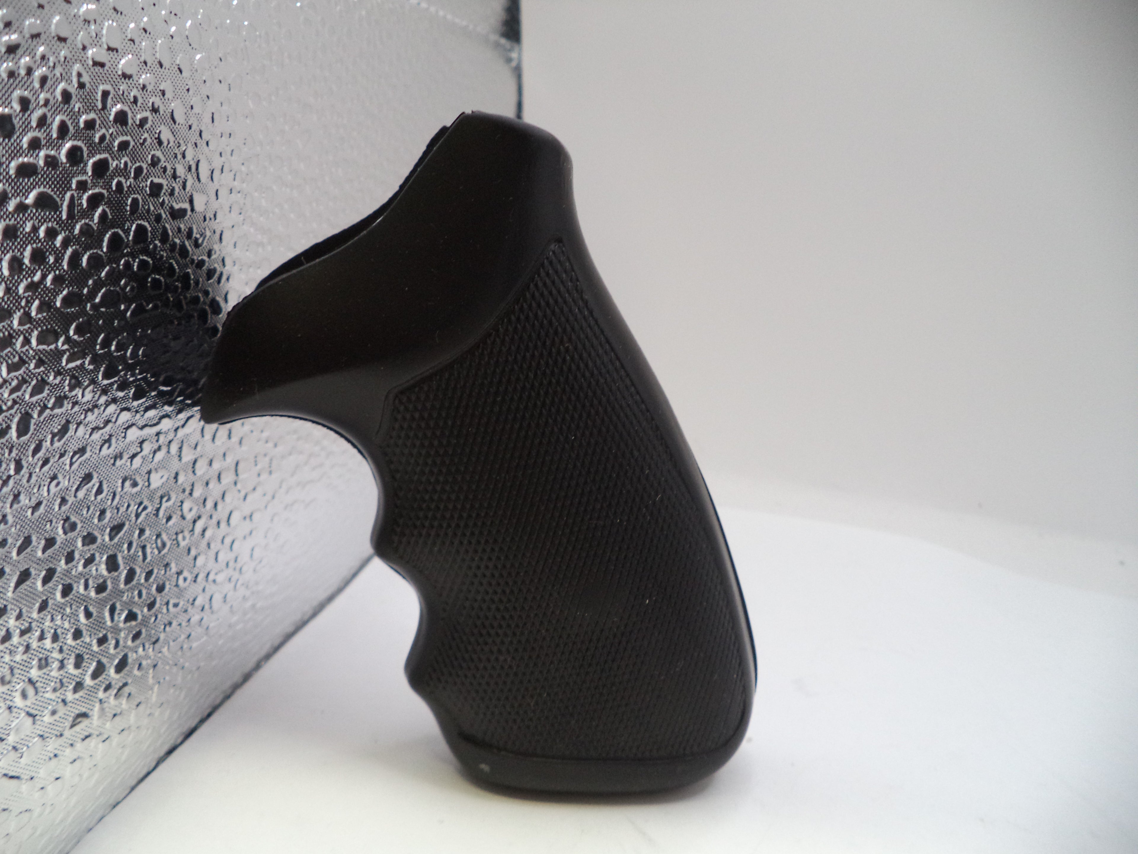 Black slip-on shoe on a white surface with a textured gray background