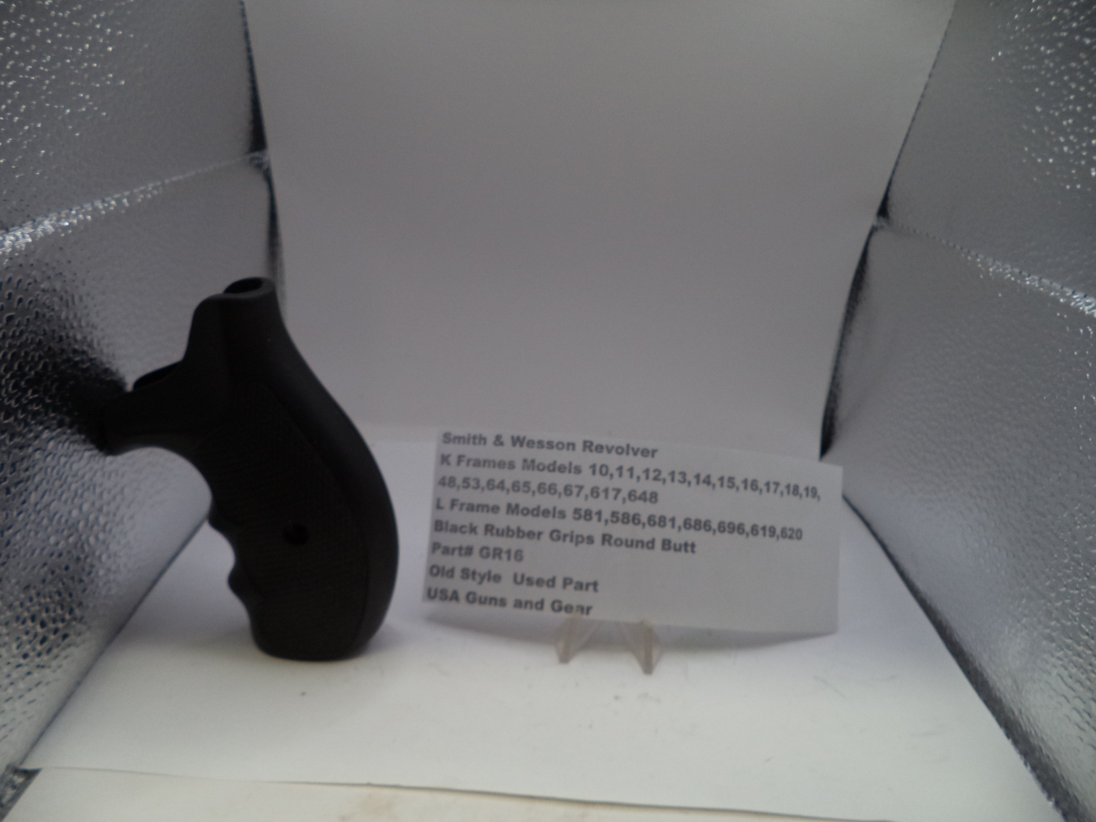 Black gun grip on a white surface with a label in front