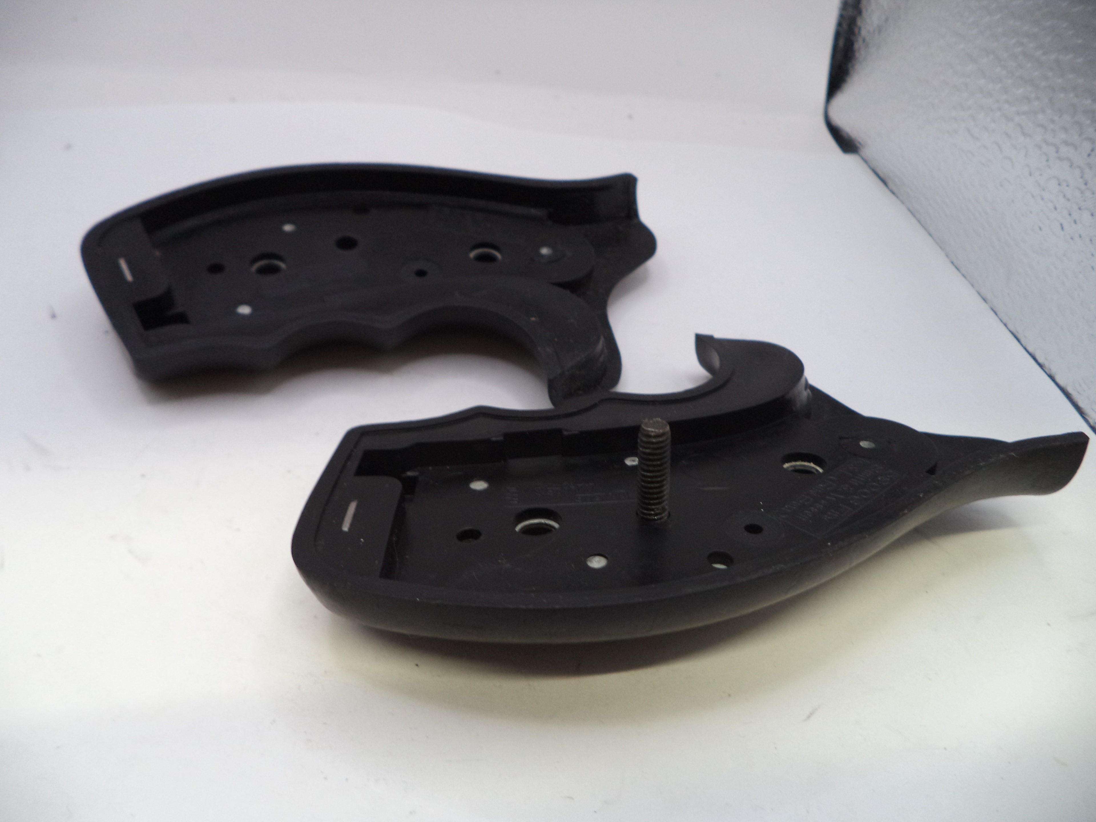 Two black plastic components on a white surface