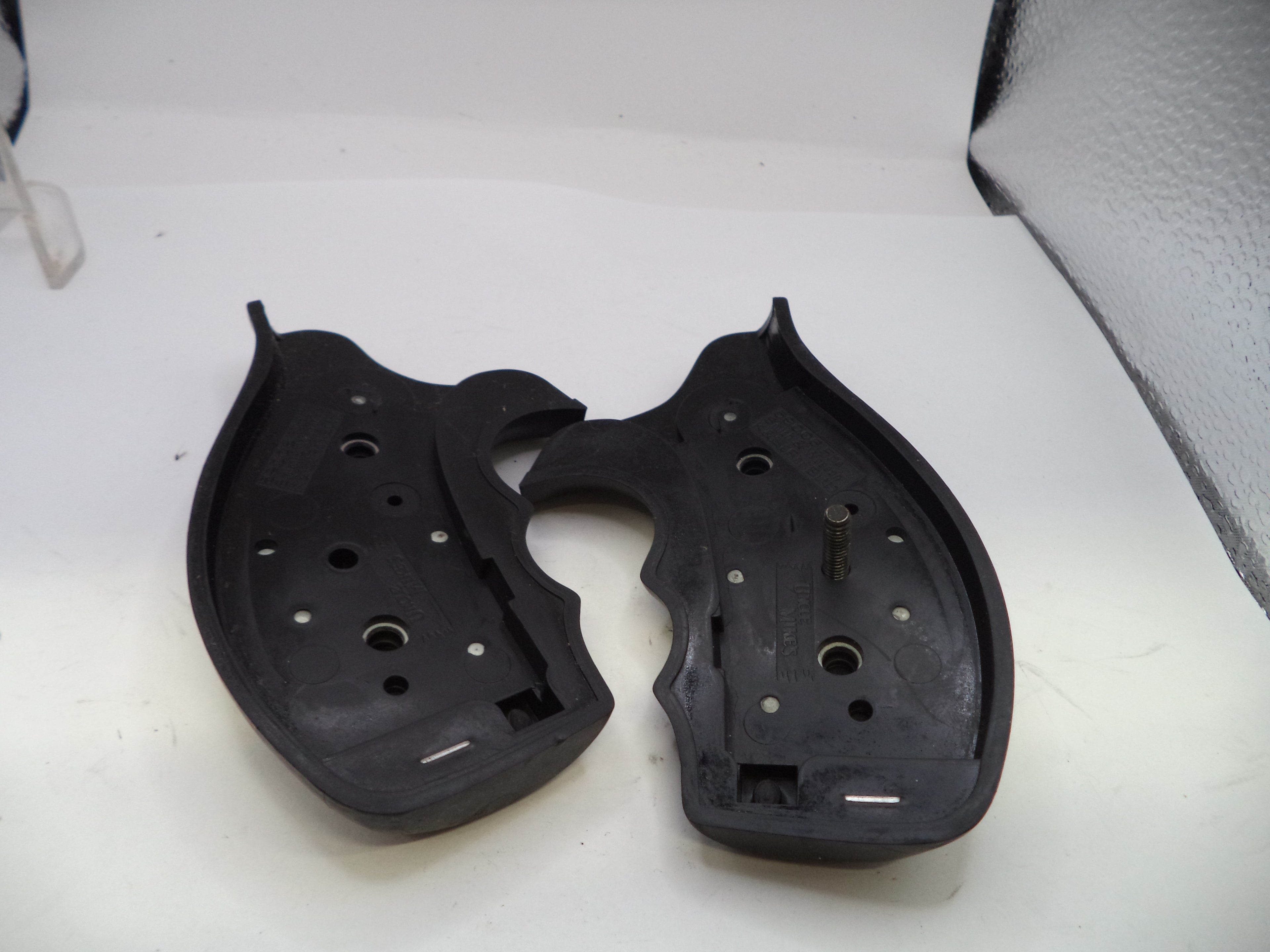 Two black plastic components on a white surface