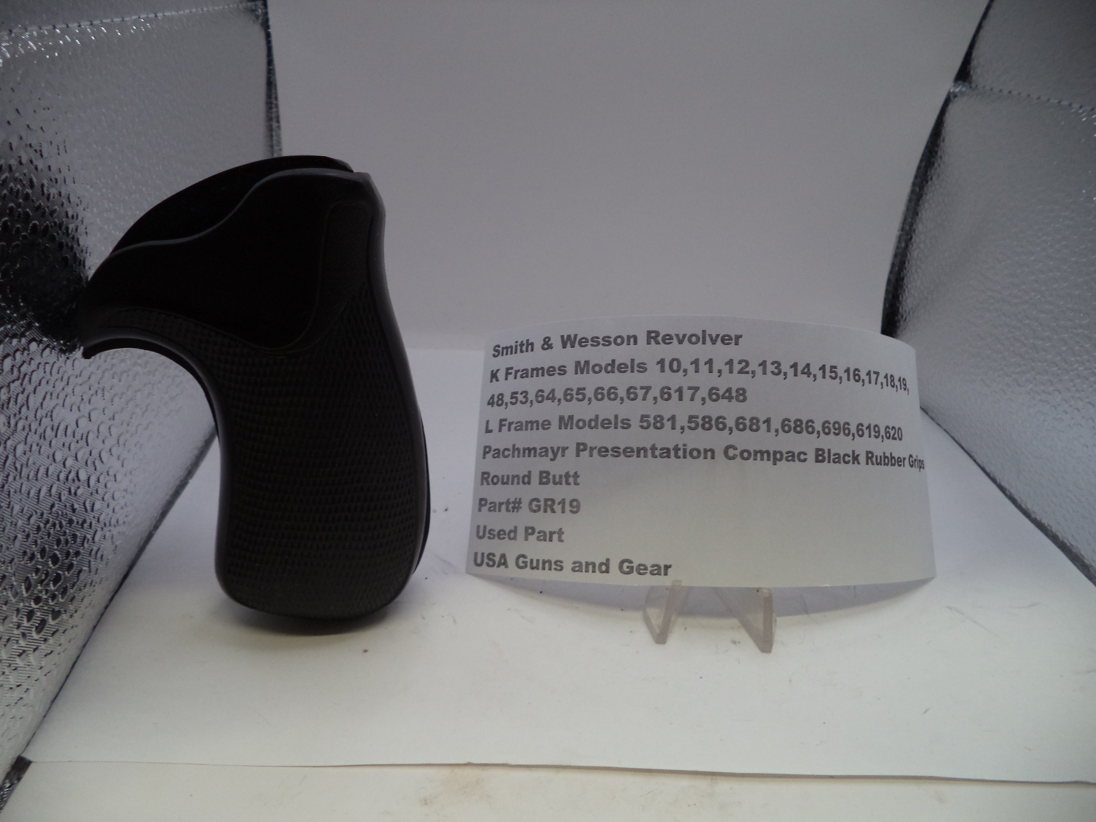 Black revolver grip and information card on a white surface