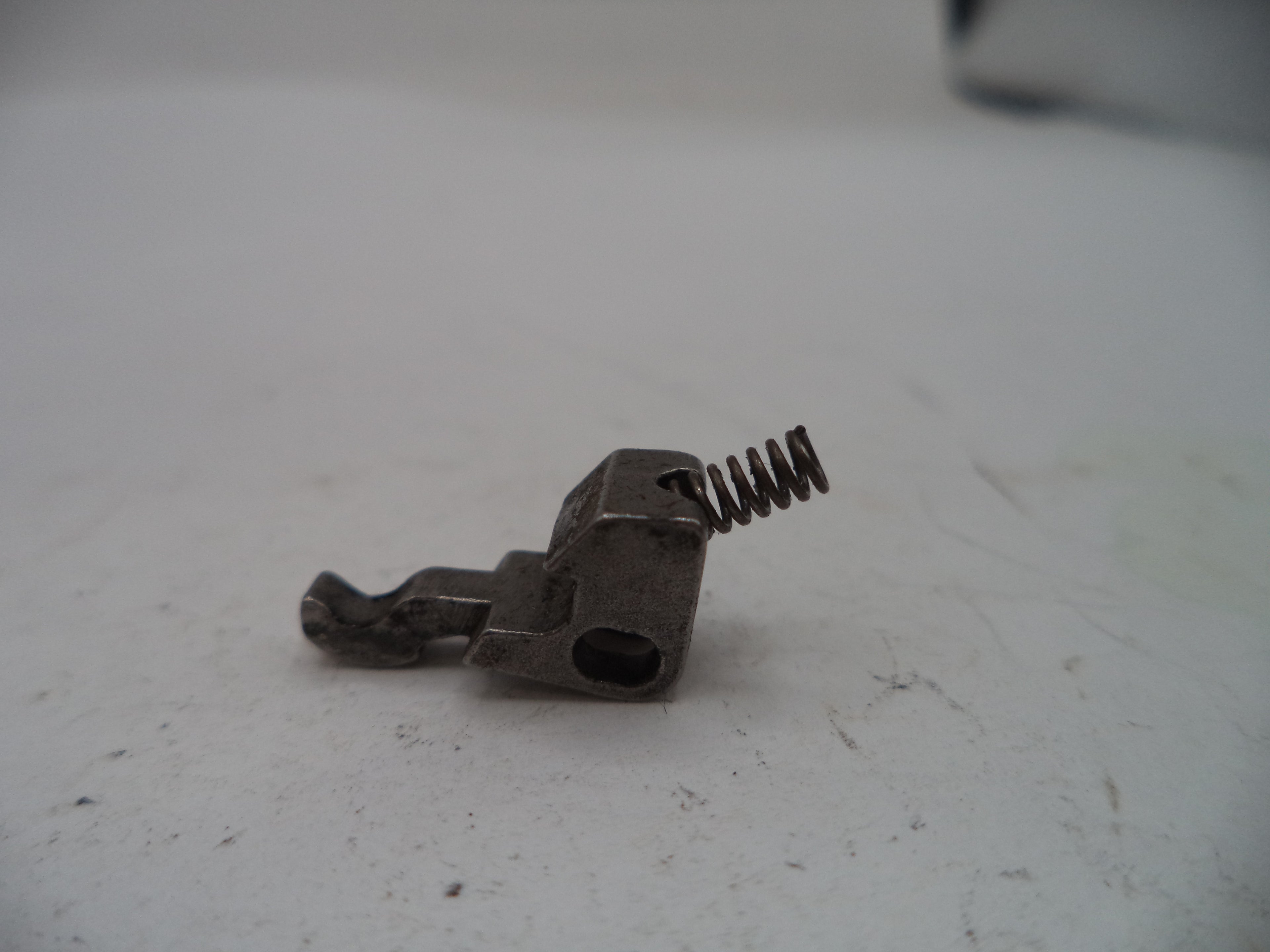 Metal component with a spring on a white surface