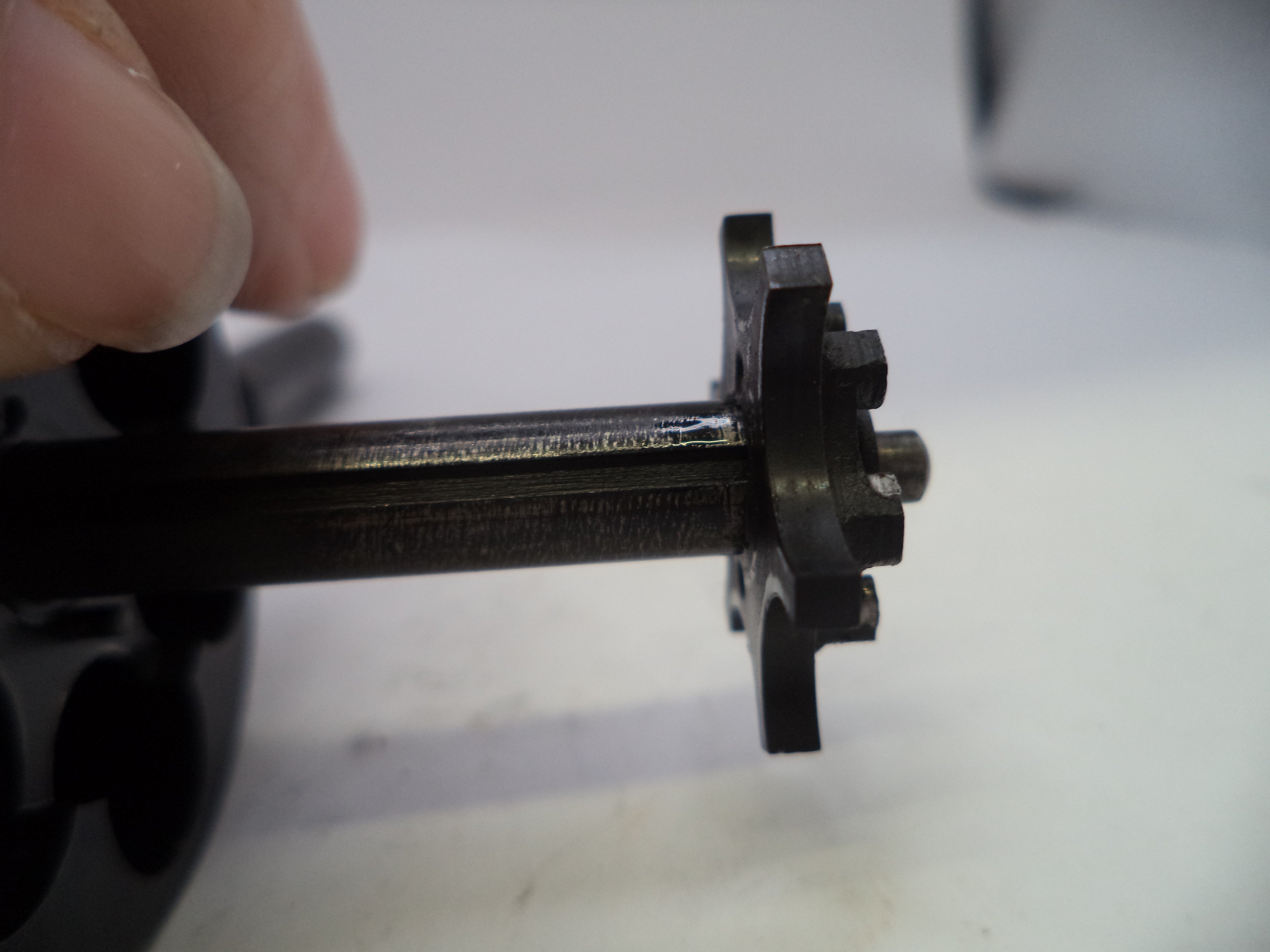 Close-up of a mechanical component held by a hand on a white background