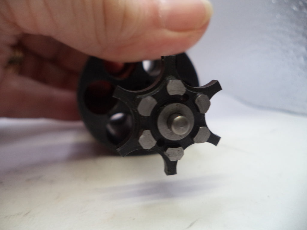 Black metal wheel or gear held by a hand on a white background