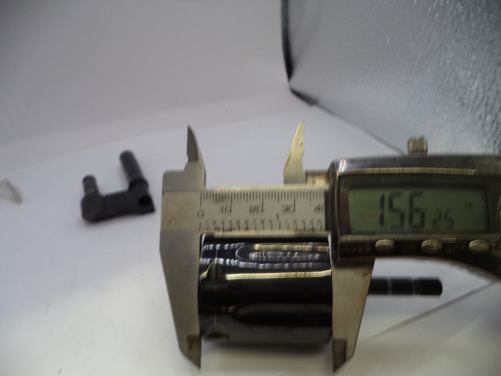 Digital caliper measuring a small metal component on a white surface