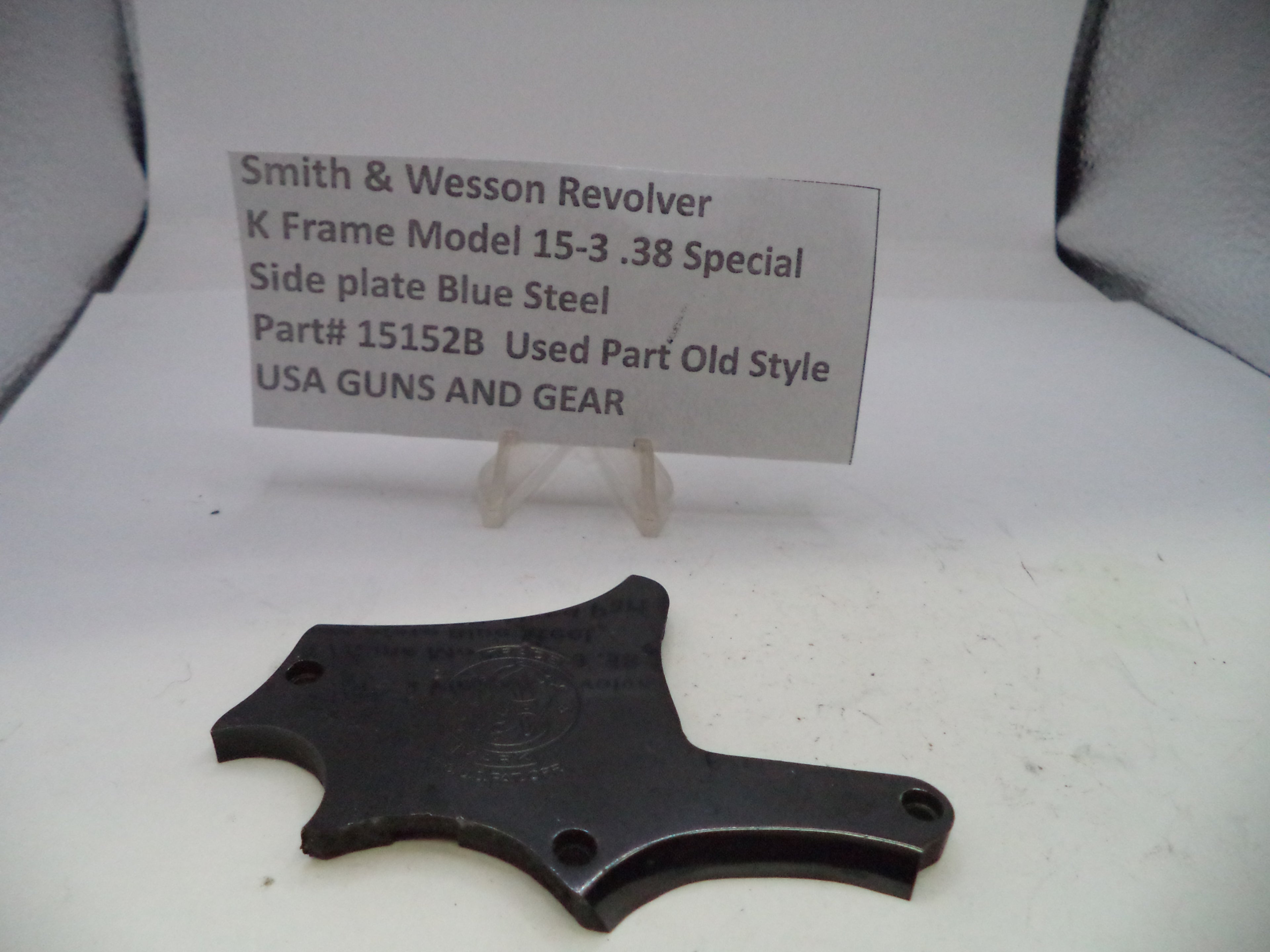 Black side plate for a Smith & Wesson revolver on a white background with a label.