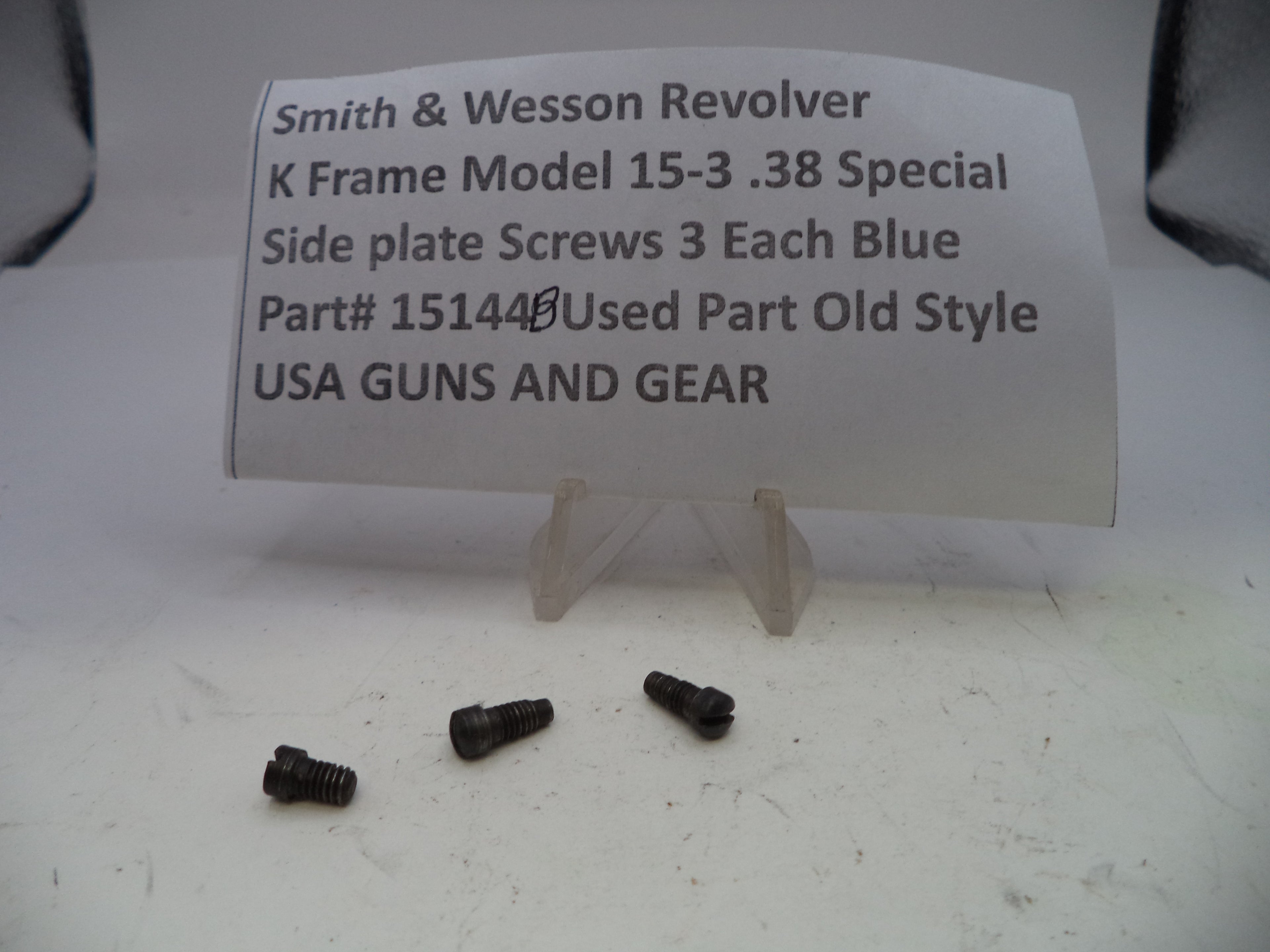 Three screws on a white surface with a label describing Smith & Wesson Revolver K Frame Model 15-3 .38 Special side plate screws.