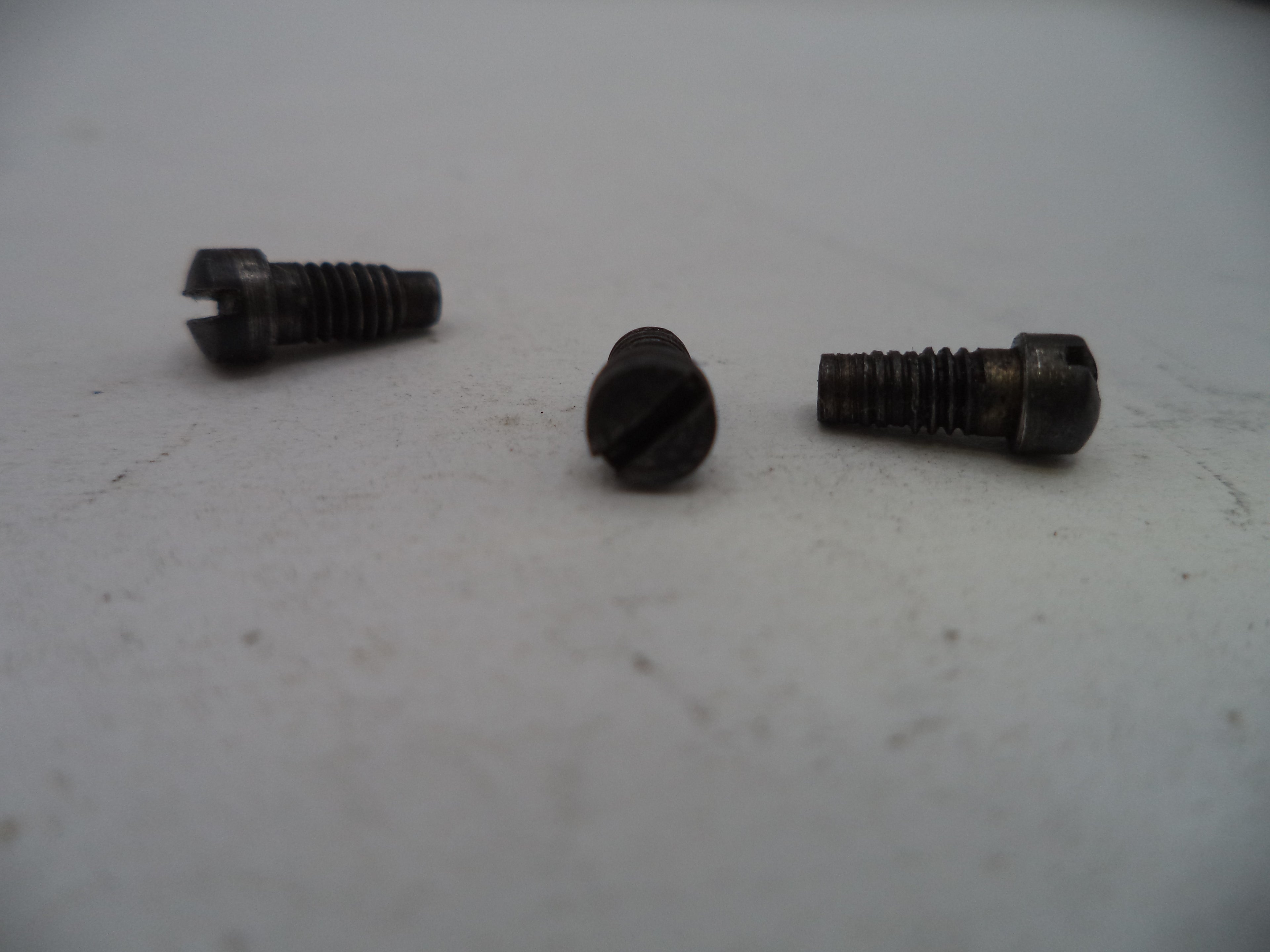 Three metal screws on a light gray surface