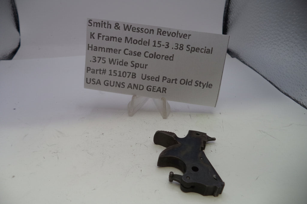 Black gun part on a white surface with a descriptive card in the background.