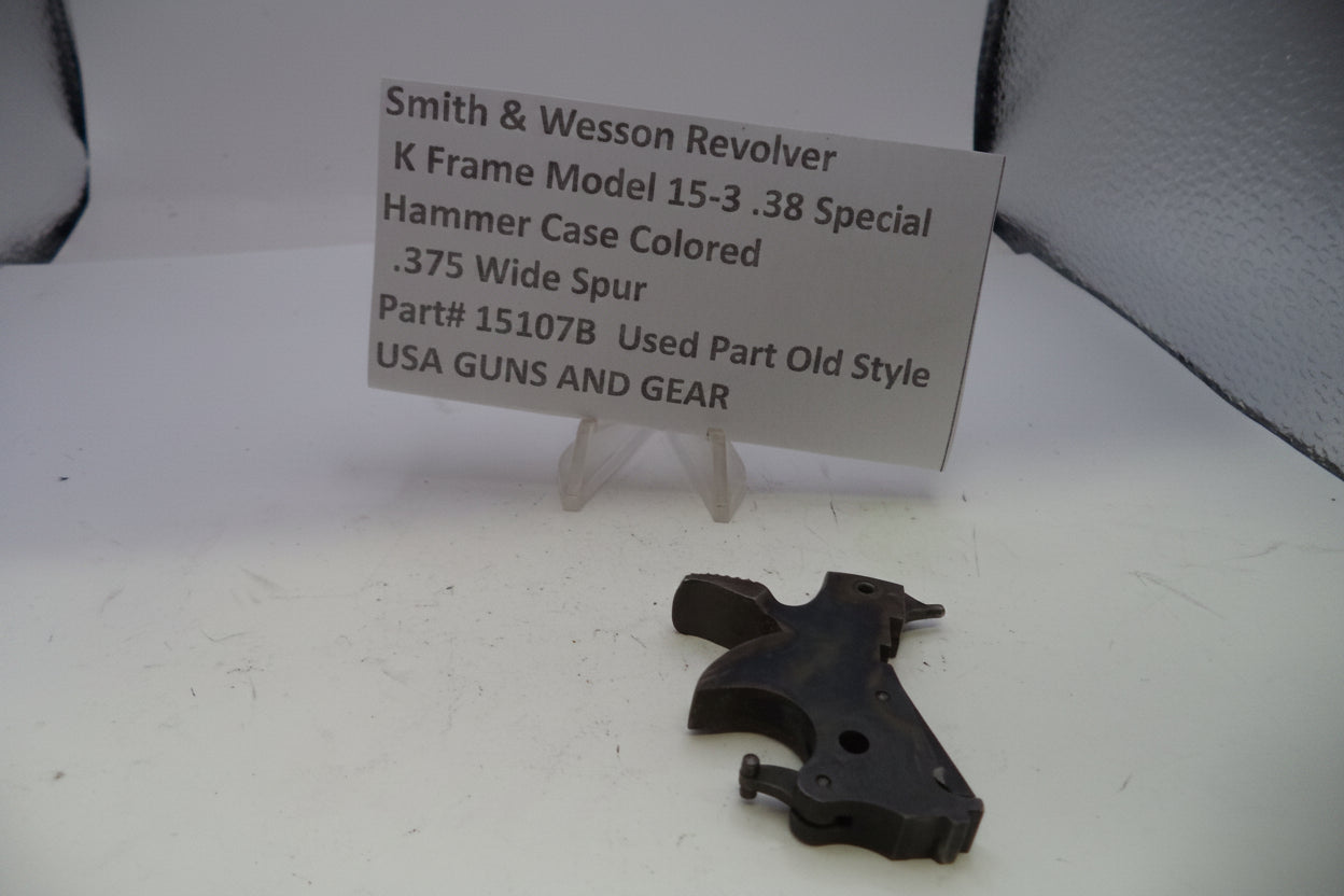 Black gun part on a white surface with a descriptive card in the background.