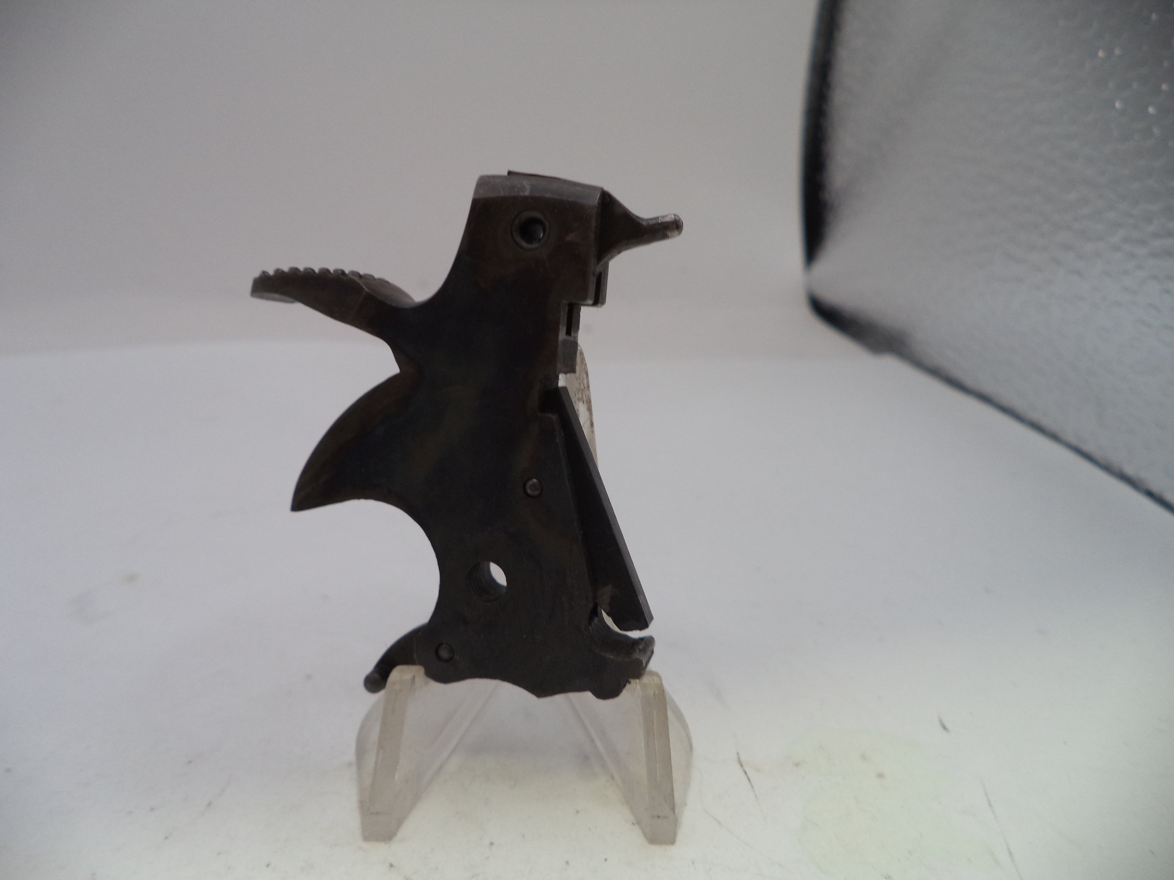 Black metal component on a clear stand against a white background
