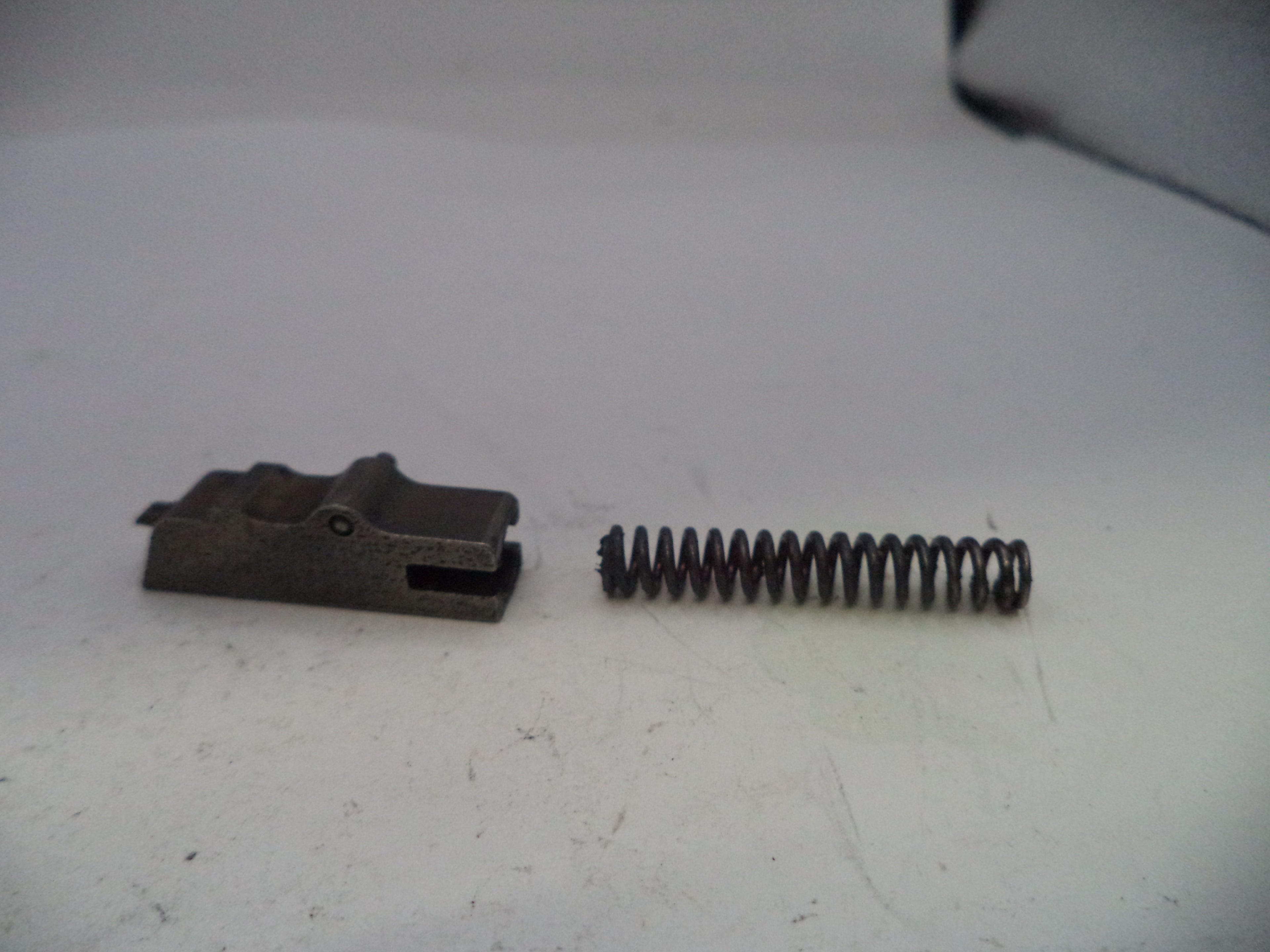 Metal component and spring on a white surface