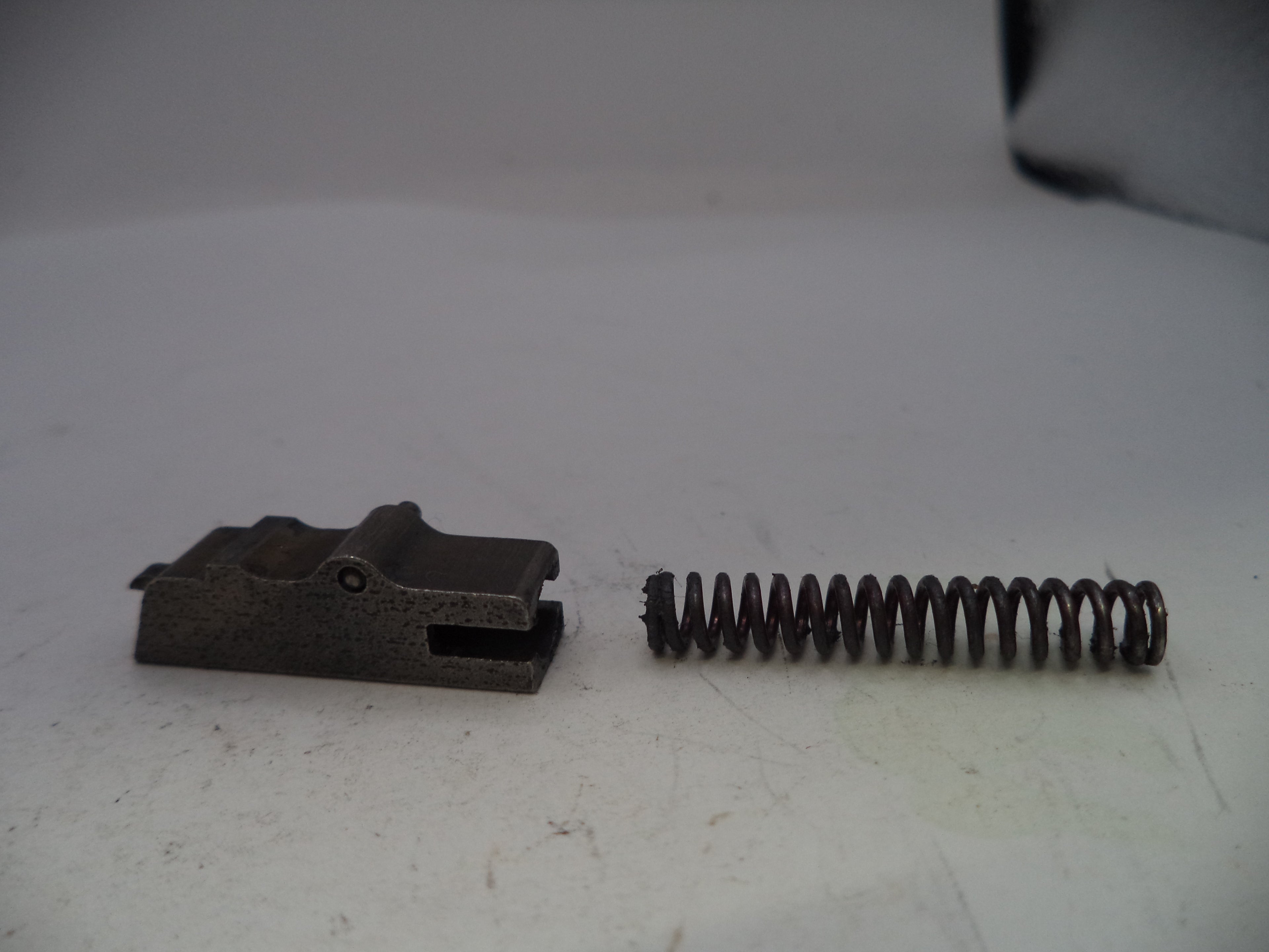 Metal brake pad and spring on a white surface