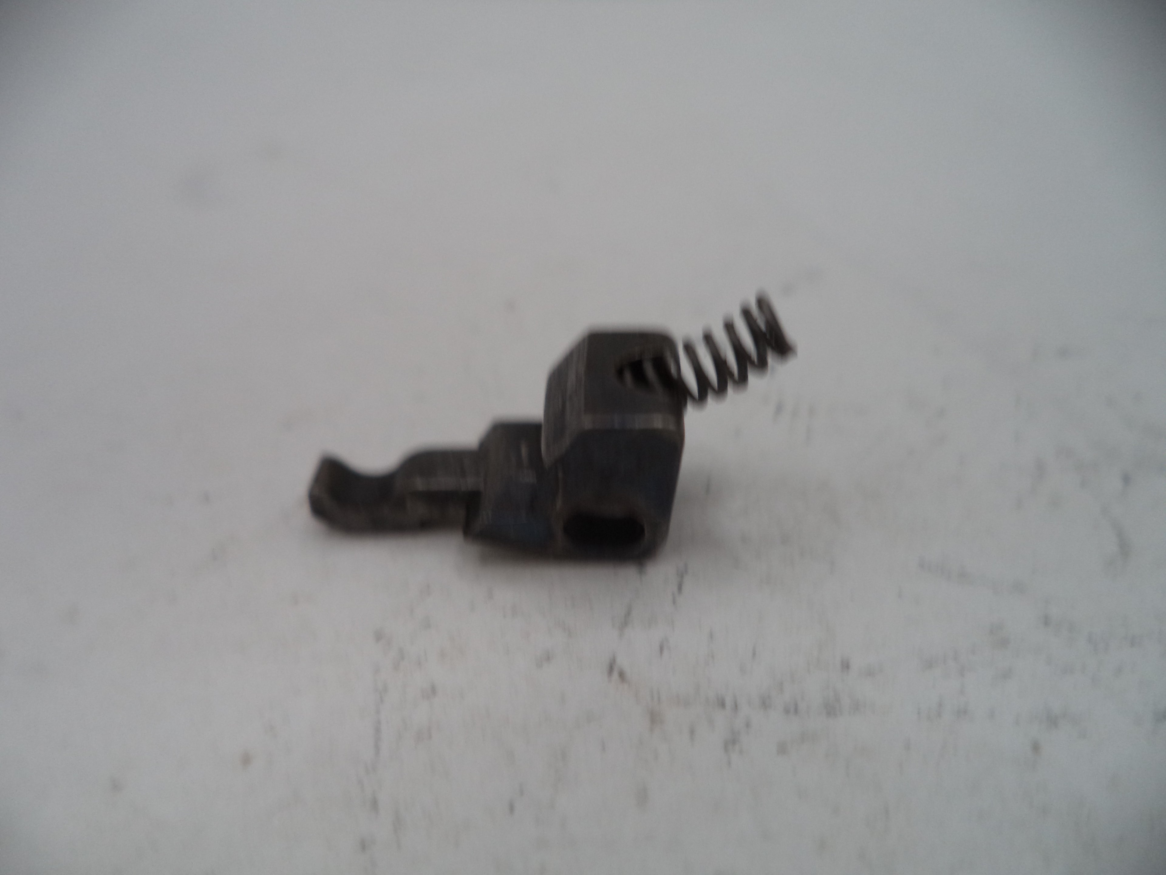 Small mechanical component with a spring on a light gray surface