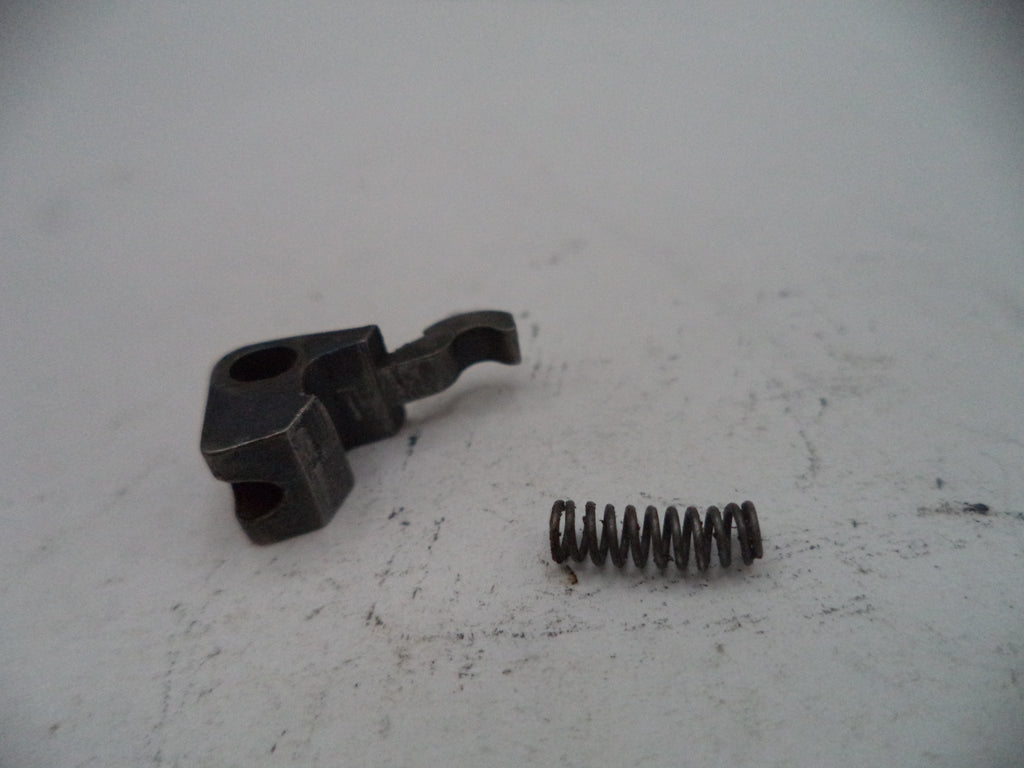 Mechanical parts including a black metal bracket and a coiled spring on a white surface.